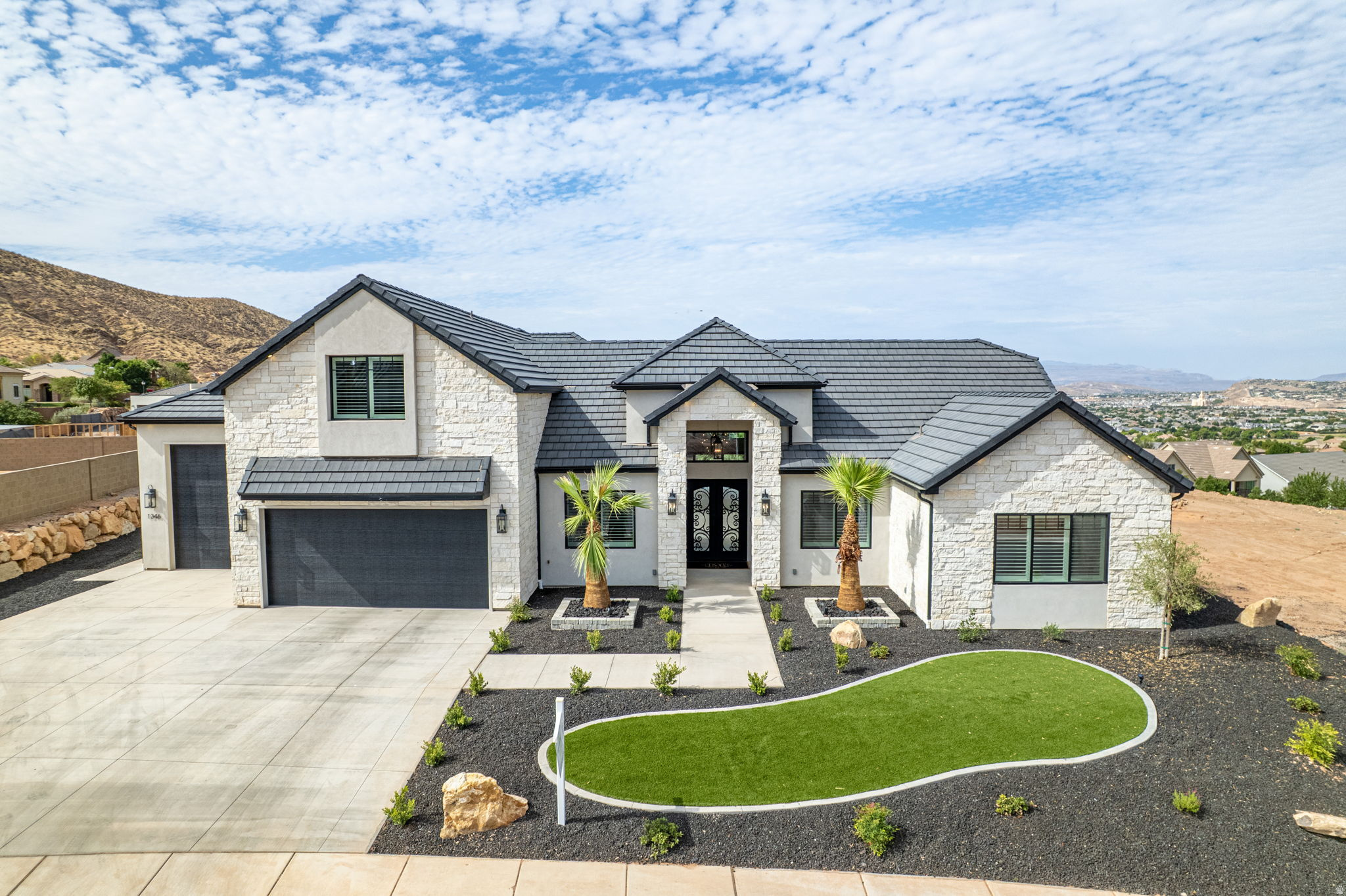 Welcome to an extraordinary custom home where luxury, design and views collide. Double iron doors and a stunning wood and tile entry set the tone from the moment you arrive. The showstopping great room features soaring 14-foot ceilings, a floor-to-ceiling white stone fireplace, and disappearing pocket doors in both the great room and dining room for true indoor/outdoor living. The kitchen is fully loaded with Taj Mahal quartzite countertops, Wolf double ovens and cooktop, Sub-Zero refrigerator, ice machine and reverse osmosis water filtration, all flowing seamlessly on gorgeous white oak engineered hardwood floors. The home gym welcomes you with wall-to-wall mirror, heavy duty rubber mat flooring and mini split. The primary suite offers a cozy fireplace, garden tub, walk-in shower, dual sinks and a spacious walk-in closet. Outside is an entertainer's dream! 18x35 heated Gunite pool, raised hot tub, outdoor kitchen with gazebo, paver patio and sweeping views framed by mature palms. Built with 2x6 construction for superior quality by Bird Homes The 4-car garage with 38-foot bay features epoxy flooring and insulation, plus the home features a built-in speaker system. Add HVAC zoning, a rooftop deck and panoramic views and no HOA and this home checks every box. Minutes from Costco, the mall, SGU airport and the upcoming Paseo shopping district in the Crimson Cliffs High School boundaries.
