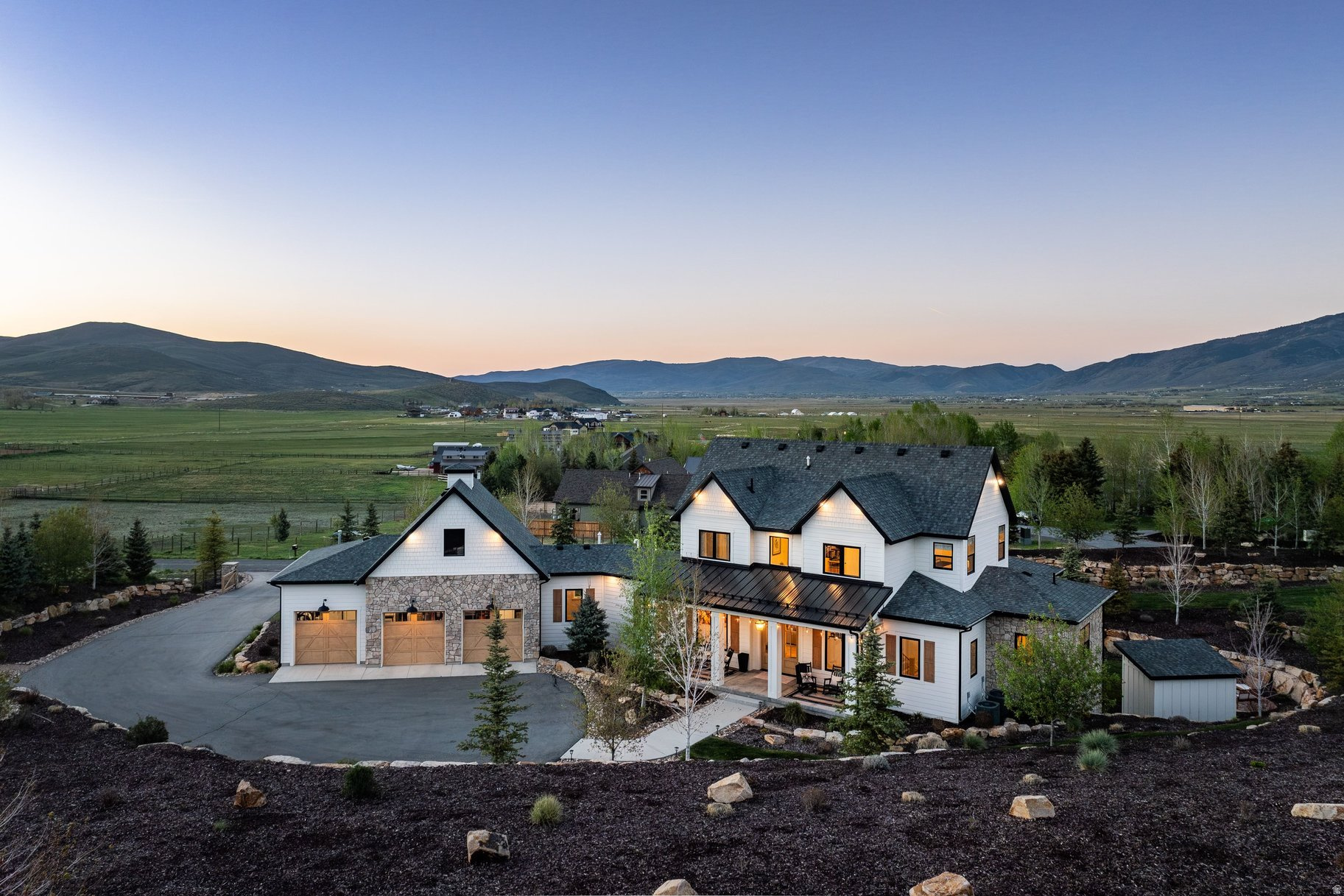 Refined Country Living Near Park City with Forever Scenic Views This custom modern farmhouse, featured in the Park City Showcase of Homes, is situated adjacent to Ure Ranch, an 835-acre preserved agricultural heritage ranch offering forever protected views, open space, and abundant wildlife habitat. Located at the entrance of Kamas Valley near Ballerina Farm and just 15 minutes from downtown Park City, the privately gated property combines quiet country serenity with convenient access to skiing, golf, hiking, biking, fishing, dining, and year-round recreation right outside your door. Offered furnished and exceptionally well cared for, the home blends timeless farmhouse character with polished modern design through a warm palette of wood, brick, stone, and steel. The grounds are beautifully designed with soft rolling green landscaping, mature trees, multiple patios and decks, a private hot tub retreat, designer shed, and a stone walkway leading to a scenic overlook gazebo with sweeping valley views. Thoughtful outdoor gathering spaces create a true sense of privacy and connection to the surrounding landscape. Filled with natural light and designed for effortless main-level living, the home features a spacious great room, chef's kitchen, and seamless indoor-outdoor living spaces ideal for entertaining or peaceful evenings at home. The main-level primary suite offers serene mountain views, a spa-inspired bath with soaking tub and oversized shower, and a generous walk-in closet. Upstairs are two guest bedrooms and a dedicated office with elevated views and abundant natural light. The walk-out lower level is designed for entertaining with a spacious family room, wet bar, game area, theater room, and a hidden brick wine and whiskey room inspired by a 1920s speakeasy. Two additional guest bedrooms and flexible secondary living spaces provide comfort and privacy for family and guests. Buyers considering homes in Hideout or Tuhaye should add this exceptional Kamas Valley property to their list.