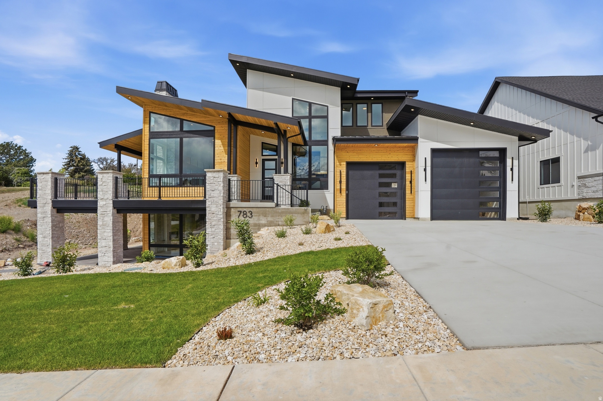 Welcome to this stunning modern home that perfectly blends style, space, and functionality with a warm, inviting feel throughout. From the moment you step inside, you're greeted by an open, airy layout paired with high-end finishes that make every space feel both elegant and comfortable. Enjoy true main-level living with a spacious primary suite, complete with its own private laundry for added convenience. The heart of the home is a chef's dream kitchen featuring an impressive 60 sq ft island, an 8-burner stove with four ovens, a working pantry with a beverage cooler, and plenty of room to gather, entertain, and create lasting memories. Car enthusiasts and hobbyists will appreciate the rare 3.5-car garage with soaring 16-foot ceilings-offering exceptional space for storage, toys, or even a workshop. Also included is a 220 outlet, and a washing station. Step outside to 682 sq ft of covered wraparound deck space, complete with a fireplace-perfect for year-round outdoor dining, relaxing, or taking in the views. Downstairs, a 610 sq ft covered patio provides direct basement access and even more room to unwind or entertain. Upstairs, two generously sized bedrooms each feature their own private ensuite bathrooms, making them ideal for guests or family members. A cozy loft adds flexible space for a reading nook, home office, or play area. The fully finished basement is designed for entertaining, offering three additional bedrooms-one perfectly suited for a future home theater-along with three bathrooms, a second laundry area, and a large family or activity room. Outside, enjoy the added value of full front yard landscaping and partial backyard landscaping, along with built-in concrete planter boxes ready for your personal touch-creating a move-in-ready outdoor space that complements the home's beautiful design. This thoughtfully designed home offers versatility, comfort, and luxury at every turn-don't miss your opportunity to make it yours.