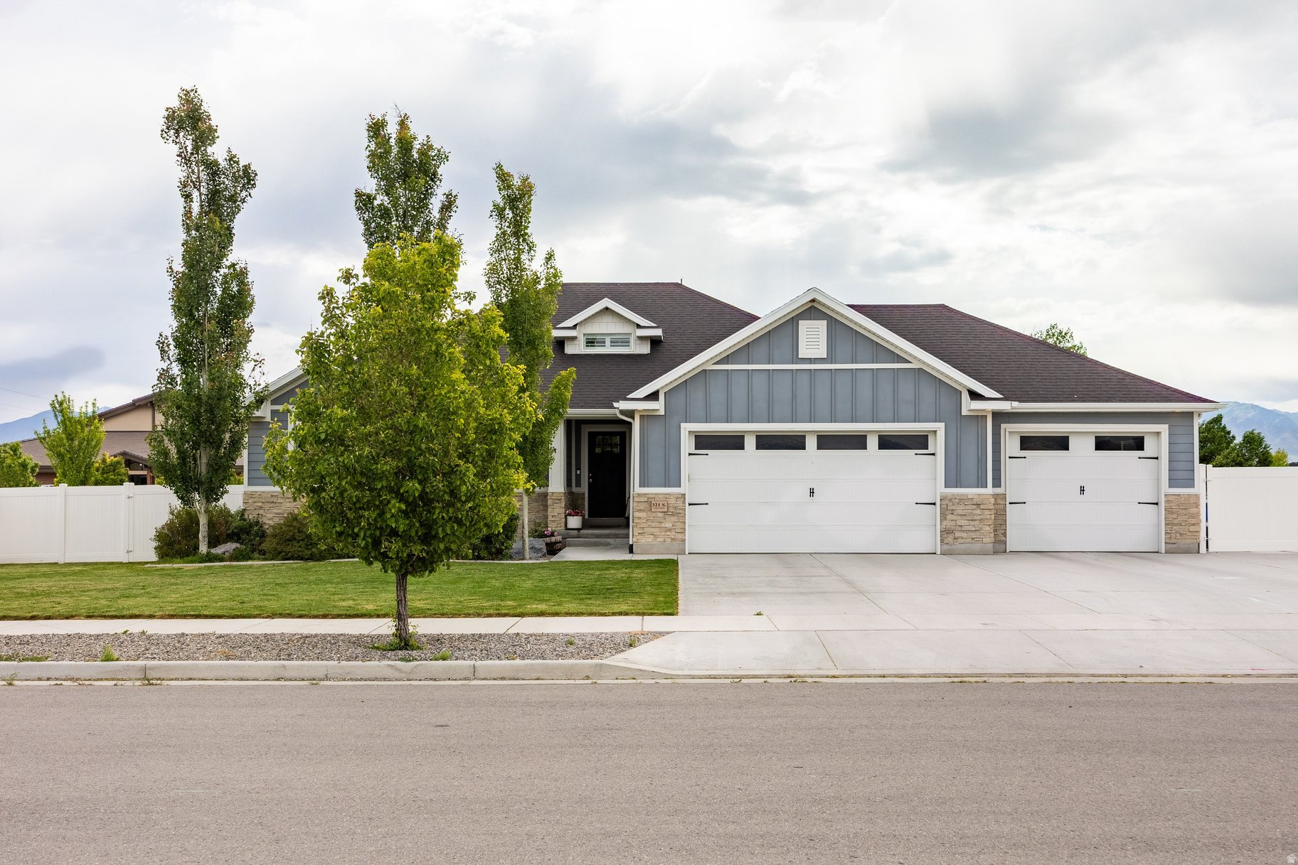 For those drawn to the idea of quieter streets, larger lots, and a home that feels established from day one, this Grantsville rambler offers a lifestyle that's becoming increasingly difficult to find near the Salt Lake Valley. Set on a fully fenced half-acre lot with mature landscaping, producing fruit trees, paved RV parking, irrigation water share, and no HOA, the property blends comfort, functionality, flexibility, and character with plenty of room to grow. Inside, soaring vaulted ceilings in the entryway make an immediate impression, welcoming you into light-filled living spaces with warm LVP flooring, a wood beam accent, and an open-concept layout designed for everyday living and gathering alike. The kitchen serves as the heart of the home with granite countertops, an oversized island, floating shelves, and a reclaimed wood pantry door, while shiplap accents, wood paneling, custom tilework, and shutters add warmth and personality throughout. Designed for easy main-level living, the home features a private primary suite filled with natural light, main-level laundry, and six spacious bedrooms with three bathrooms total, offering flexibility for guests, hobbies, work-from-home needs, or simply room to grow. The finished basement expands the living space with a projector and screen for the perfect home theater setup, a dry bar area, and a large storage room. Outside, the fully landscaped yard, mature trees, pergola, gas firepit, and established outdoor spaces create a move-in ready experience where the work has already been done and the home can be enjoyed from day one. A French door creates an effortless connection from the main living space to the backyard, while the irrigation water share adds practicality and long-term value for maintaining the lush landscaping with ease. If you find yourself craving a little more breathing room without giving up convenience, this home offers the balance of peaceful small-town living with an easy commute back to the Salt Lake Valley, all within a property that feels established, inviting, and ready to enjoy from the moment you arrive.