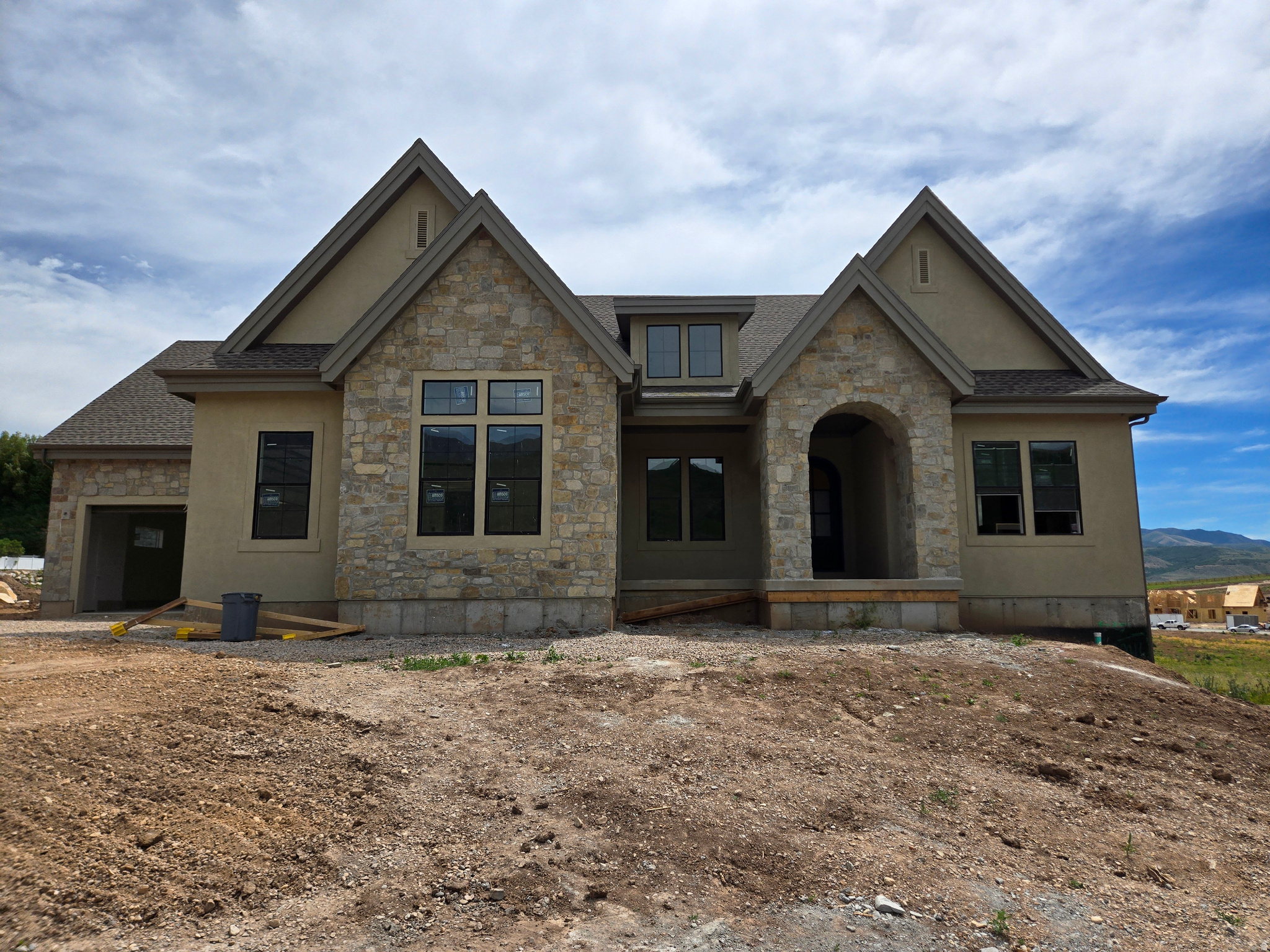 LOT#9 in Frontier Estates, one of Mountain Green's newest communities, nestled in the foothills of Snowbasin, a world-class ski resort. Built by renowned local builder, Symphony Homes, known for excellent craftsmanship and interior design. This home is currently under construction and estimated completion is August 2026. Beautiful curb appeal with a European Romantic elevation. True 4-car garage (two 2-car doors) will be finished to paint with epoxy floors. Walkout basement. 30'x14' covered deck. Gourmet galley kitchen with a 48" dual fuel range and built-in column fridge and freezer. Large butler's pantry with beverage fridge. Raised ceiling heights throughout and 13' ceiling in family room will have a stain-grade beam ceiling. Large dining nook. Impressive Owner's Suite features a fireplace, decorative beam ceiling, spa-like bathroom with a large walk-in tile shower, oversized free-standing tub, separate vanities, and huge wardrobe room with washer/dryer hookup for convenience. Huge suspended slab basement can be an ADU with its own separate entrance direct from the garage or from the covered patio, featuring a full kitchen, laundry room, 3 bedrooms (two of them with own en-suite bathrooms and walk-in closets), and also has a finished gym and a theater room. List price includes 150k in full yard landscaping. Also equipped with active radon system and upgraded insulation.