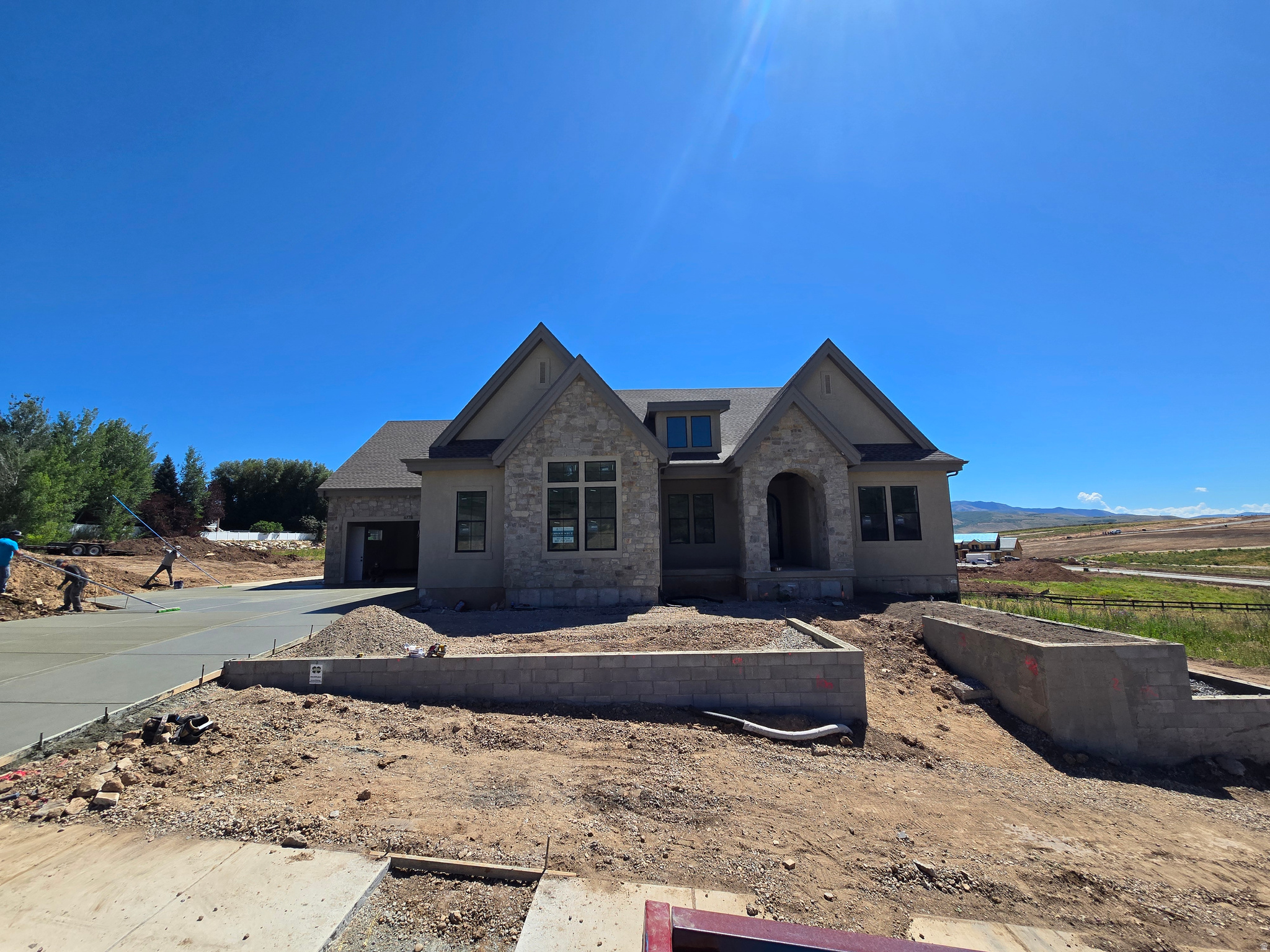 LOT#9 in Frontier Estates, one of Mountain Green's newest communities, nestled in the foothills of Snowbasin, a world-class ski resort. Built by renowned local builder, Symphony Homes, known for excellent craftsmanship and interior design. This home is currently under construction and estimated completion is August 2026. Beautiful curb appeal with a European Romantic elevation. True 4-car garage (two 2-car doors) will be finished to paint with epoxy floors. Walkout basement. 30'x14' covered deck. Gourmet galley kitchen with a 48" dual fuel range and built-in column fridge and freezer. Large butler's pantry with beverage fridge. Raised ceiling heights throughout and 13' ceiling in family room will have a stain-grade beam ceiling. Large dining nook. Impressive Owner's Suite features a fireplace, decorative beam ceiling, spa-like bathroom with a large walk-in tile shower, oversized free-standing tub, separate vanities, and huge wardrobe room with washer/dryer hookup for convenience. Huge suspended slab basement can be an ADU with its own separate entrance direct from the garage or from the covered patio, featuring a full kitchen, laundry room, 3 bedrooms (two of them with own en-suite bathrooms and walk-in closets), and also has a finished gym and a theater room. List price includes 150k in full yard landscaping. Also equipped with active radon system and upgraded insulation.