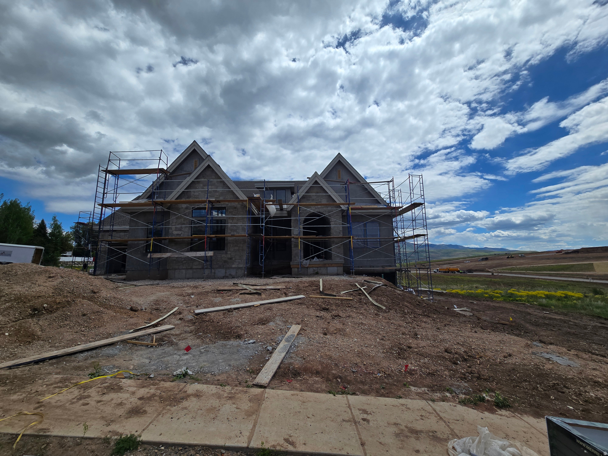 LOT#9 in Frontier Estates, one of Mountain Green's newest communities, nestled in the foothills of Snowbasin, a world-class ski resort. Built by renowned local builder, Symphony Homes, known for excellent craftsmanship and interior design. This home is currently under construction and estimated completion is August 2026. Beautiful curb appeal with a European Romantic elevation. True 4-car garage (two 2-car doors) will be finished to paint with epoxy floors. Walkout basement. 30'x14' covered deck. Gourmet galley kitchen with a 48" dual fuel range and built-in column fridge and freezer. Large butler's pantry with beverage fridge. Raised ceiling heights throughout and 13' ceiling in family room will have a stain-grade beam ceiling. Large dining nook. Impressive Owner's Suite features a fireplace, decorative beam ceiling, spa-like bathroom with a large walk-in tile shower, oversized free-standing tub, separate vanities, and huge wardrobe room with washer/dryer hookup for convenience. Huge suspended slab basement can be an ADU with its own separate entrance direct from the garage or from the covered patio, featuring a full kitchen, laundry room, 3 bedrooms (two of them with own en-suite bathrooms and walk-in closets), and also has a finished gym and a theater room. List price includes 150k in full yard landscaping. Also equipped with active radon system and upgraded insulation.