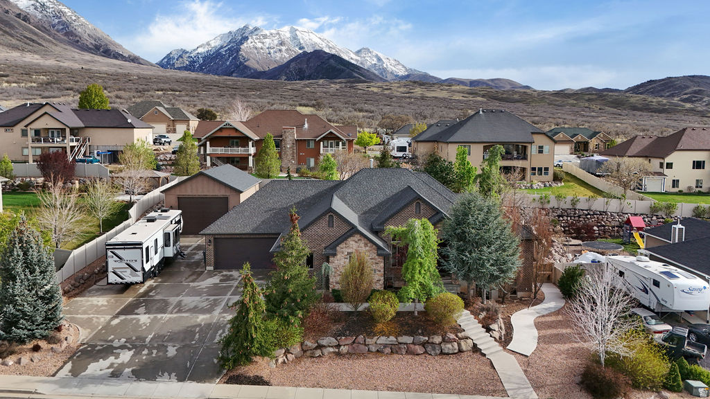 Be sure to check out the 3D and drone video tours by clicking on the tour button. This original-owner custom home is ideally situated on a quiet street in one of Santaquin's most desirable areas near the mouth of the canyon, offering stunning views and a spacious .41-acre lot with beautifully landscaped grounds, mature trees, and garden boxes. The full brick exterior is complemented by an enormous attached six-car garage with a rear pull-through door, along with a separate detached three-car garage/workshop equipped with a rail hoist and dust collection system. Inside, the home features 9-foot ceilings throughout, with select spaces opening up to impressive 14-foot ceilings. Additional highlights include plantation shutters, whole-home audio, and a thoughtfully designed layout with a formal living room or office off the foyer. The kitchen is well-appointed with double ovens, a separate gas range, granite countertops, and a tile backsplash, while the inviting living spaces include both a gas fireplace and a wood-burning stove. The spacious master suite offers a walk-in shower, separate tub, double vanities, and a walk-in closet. The fully finished walkout basement boasts 9-foot ceilings, an exercise room, and is already stubbed for a kitchenette, offering excellent potential for an accessory apartment. Additional highlights include a huge covered patio, 2x6 exterior construction with upgraded insulation, a water softener, and built-in laundry cabinetry, making this home a rare combination of quality, space, and versatility.