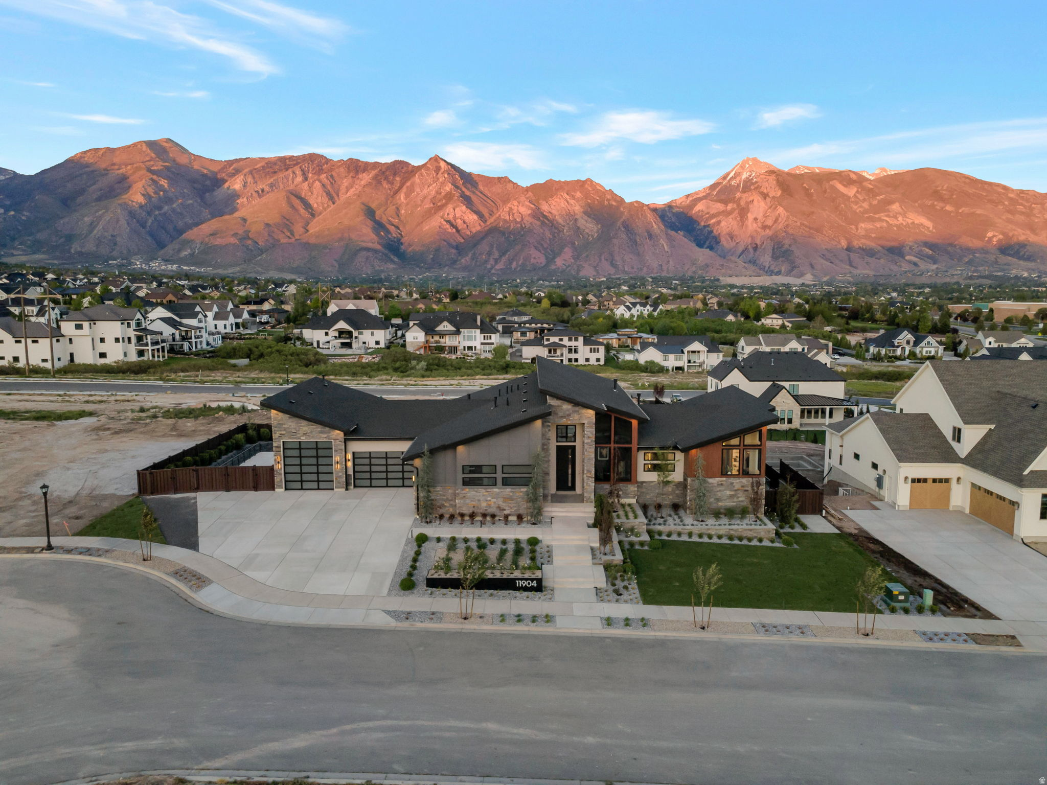 Symphony Homes newest feature home in an incredible location, where thoughtful design meets everyday livability. Clean modern architecture, expansive windows, and curated finishes create a space that feels both elevated and comfortable. Designed with functionality in mind, the main level offers a dedicated office with custom built-ins, a butler's pantry with hidden access, and a practical mudroom. The open kitchen and great room flow seamlessly to the outdoor living spaces, making entertaining effortless. The primary suite is a standout, with a private sitting area and fireplace, spa-inspired wet room, and an expansive wardrobe room with in-suite laundry that feels more like a boutique than a traditional closet. The walkout lower level is equally impressive, featuring a gym beneath a suspended slab, an open theater with  a projector, wet bar, and generous gathering spaces. Outside, enjoy a  acre fully landscaped yard with swimming pool, outdoor kitchen, patio with gas firepit, and an expansive covered deck designed for year-round use, offering spectacular mountain views. A finished (and heated) garage with epoxy flooring, utility sink, RV garage  (12'H door, 40'8"L) and an additional hidden "toy" garage in the backyard completes the home.