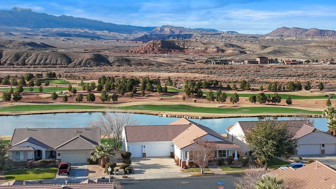 Truly one of a kind in Sun River's premier 55+ community, this rare 4-bedroom, 4.5-bath walkout basement home offers 4,060 sq ft of beautifully updated living space, including 2,108 sq ft on the main level. Recent upgrades include a remodeled kitchen, and refreshed bathroom's. Large windows capture stunning views of the golf course, ponds, and Pine Valley Mountain, filling the home with natural light and showcasing Southern Utah's scenery. The thoughtful floor plan offers multiple family rooms, inviting sitting areas, and formal dining spaces, creating ideal flow for both everyday living and entertaining. The walkout basement features a wet bar and a versatile flex room perfect for hobbies, fitness, office space, or additional guest use, along with exceptional storage throughout. Step outside to enjoy both a large covered deck and a covered patio below providing ideal outdoor living spaces year-round. The backyard is generously sized for the community, situated on a .13-acre lot. Enjoy the comfort of a rare, air-conditioned 3-car garage that is extra deep, offering ample room for additional workspace, storage, or recreational gear. Sun River residents enjoy championship golf, clubhouse dining, pools, fitness center, pickleball, walking trails, and an active social calendar. Southern Utah's mild winters make year-round outdoor living a highlight, while the nearby Southern Corridor exit provides quick access to new medical facilities, shopping, dining, and downtown St. George. This home offers space, views, functionality, and     lifestyle an exceptional opportunity in Sun River.