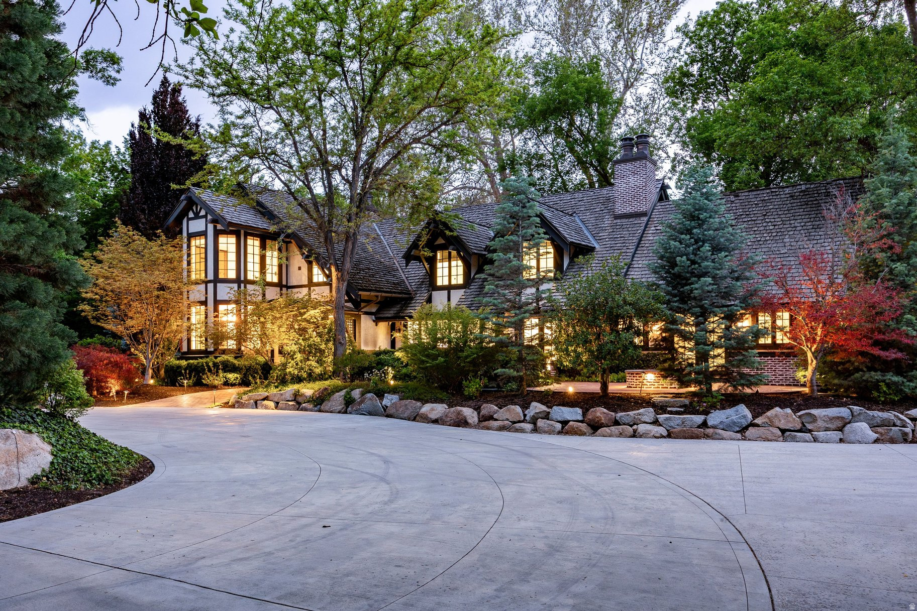 Set on nearly two private acres of lush gardens with a seasonal stream and private driveway, this estate is located in Salt Lake City's prestigious Walker Lane neighborhood. The Tudor-style estate blends timeless architecture with refined modern luxury. Originally built in 1920 and thoughtfully remodeled in 2010, the residence offers approximately 5,650 square feet with four bedrooms, three full bathrooms, two powder rooms, a dedicated office space, private theater room, multiple entertaining areas, and a two-car garage in the main home. The estate also features a detached garage that includes a beautifully finished studio with a secure safe room, wet bar, fireplace, full bathroom, and garage space for up to ten vehicles. Throughout the interior, you'll find rich wood flooring, four gas fireplaces, soaring ceilings with garden framed windows, custom finishes, and integrated smart-home technology that create a sophisticated, light-filled atmosphere. The chef's kitchen is well appointed with Thermador appliances, custom cabinetry, granite countertops, an oversized island, a walk-in pantry and a double-sided fireplace. The spacious primary suite features a fireplace, French doors to a private balcony, sun-filled sitting room, heated bathroom floors, steam shower, soaking tub, and dual walk-in closets. Outdoor living includes expansive wrap-around patios, a gas fire pit, mature trees and gardens, gorgeous lawn, raised planter boxes, and a seasonal stream offering exceptional privacy and complete tranquility. A truly rare offering in one of Utah's most distinguished residential enclaves. Photographs included in the listing contain virtually staging of furniture and other decor and are intended for illustrative purposes only.