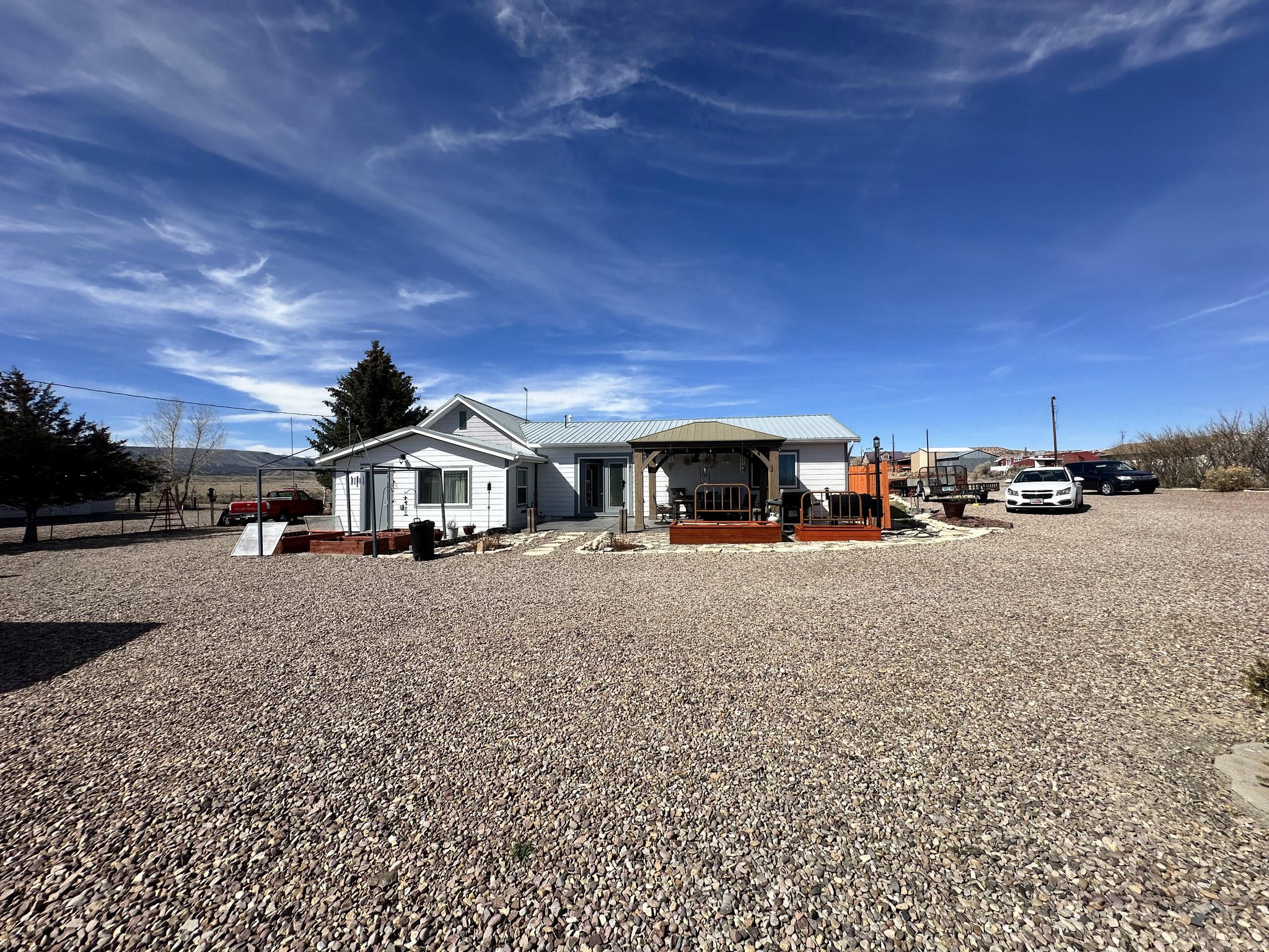 Tucked away in the peaceful charm of Manila, Utah, just a short drive from the breathtaking Flaming Gorge Reservoir, this one-of-a-kind property offers a lifestyle as inviting as its surroundings. Set on nearly half an acre, this meticulously maintained home blends comfort, creativity, and wide-open living in a way that's truly rare for the area.  Inside, you'll find a thoughtfully designed open floor plan, fully customized and expanded by the owner to create a space that feels both spacious and welcoming. The home features 2 bedrooms plus 2 versatile dens, one easily convertible into an additional bedroom, offering flexibility for guests, hobbies, or a home office. A dedicated craft room makes the perfect retreat during cozy winter days, while the family room impresses with its stunning vaulted ceiling and seamless flow into a bathroom and secondary bedroom. The bedroom layout provides added privacy, with spaces thoughtfully set apart.  Step outside and breathe in the fresh Manila air from your covered patio, surrounded by endless possibilities to garden, grow your own food, or simply relax and take in the scenic views. The property also features a workshop, two carports for all your recreational toys, a secondary outdoor water spigot, and a convenient horseshoe driveway, ideal for trailers or RVs. From the boutique-like feel of the impeccably clean interior to the expansive outdoor space full of opportunity, this home is a true standout. Whether it's the charm inside or the beauty outside, you'll find it hard to choose your favorite feature, this is a rare gem you won't want to miss.   Square footage figures are provided as a courtesy estimate only and were obtained from county records.  Buyer is advised to obtain an independent measurement.