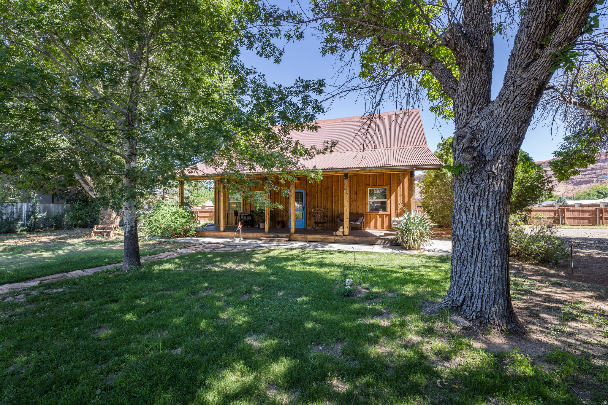 COMMERCIAL-RESIDENTIAL CHARMER ...Tucked away on nearly half an acre of  commercial-residential land in the heart of Moab, this lovely two-story home offers a rare combination of privacy, character, and convenience. Just four blocks from Main Street, this 1,735 square foot charmer feels worlds away, surrounded by mature landscaping, towering shade trees, and peaceful outdoor spaces- yet it is set on a high visibility commercial corner. Inside, the home is bright and inviting, with vaulted ceilings, exposed wood beam details, and an airy living area filled with natural light. Reclaimed wood floors, vintage doors, a classic clawfoot tub, and thoughtfully selected fixtures add warmth and authenticity throughout. The functional floor plan includes one bedroom and one bathroom on the main level, with two additional bedrooms and a bathroom upstairs. The loft style upper-level further enhances the home's open and welcoming feel. Outside, the grounds offer a private retreat with an irrigation share and water right. Mature shade trees provide welcome relief during the summer months, while established sage bushes and fruit bearing peach trees add seasonal color and enjoyment. The expansive front porch overlooks the lush lawn and creates an inviting space for outdoor living throughout the year. During winter, the property's unique position captures lingering afternoon sunlight as it sets beneath the Moab Rim. This unique property offers added flexibility in a highly desirable in town setting. With parking for at least six vehicles and a location just blocks from Main Street, this is an extraordinary opportunity to own a property that combines comfort, character, convenience, and commercial versatility in Moab's C2 zone.
