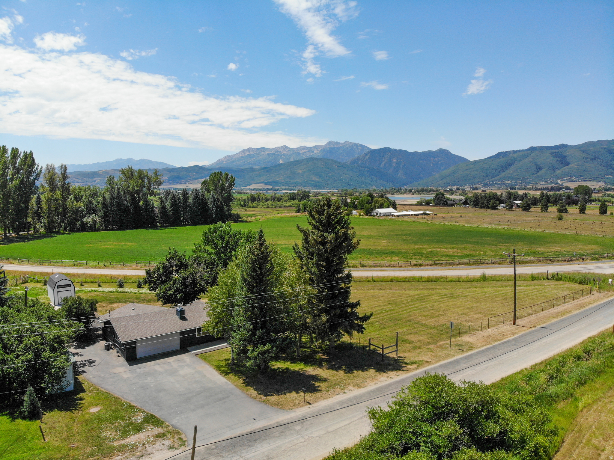 With unmatched, 360 degree mountain views, including direct views of Snowbasin Ski Resort, welcome to your picture-perfect mountain farmhouse retreat! Situated on a full acre of pristine land, the property has plenty of space for a home expansion, a detached garage or barn, or whatever you'd like to do to make it your own. When pulling into the property, you'll find a massive asphalt driveway that was recently sealed and less than three years old. The front of the home offers uninterrupted, front-row views of the Wasatch Mountains, including direct views of Geertsen and Middle Fork Canyons. The property is adjacent to the historic Bar B Ranch, which is comprised of hundreds of acres of protected land, ensuring those sweeping, idyllic pasture views remain preserved for years to come. Inside the home is an open floor plan with a recently remodeled living space, including a brand-new luxury fireplace. The entire home has brand new paint, and the kitchen was updated in the last five years. Double pain windows, furnace, and AC were all installed in 2020 and the water heater is less than a year old. The roof is less than 10 years old and heat tape was installed less than three years ago. Off the back of the home is where you can enjoy a full mountain panoramic view and a spacious back lawn that features a fire pit and a massive, brand-new storage shed for all your gear. Inside has three cozy bedrooms and an updated bathroom. The garage includes an electric heater and a a 220V outlet, ideal for electric vehicle charging or shop tools. It also includes a storage room or space for a shop. The house is also directly across from the community walking/biking path that spans the entire Ogden Valley! With the property's views, upgrades, and location, this is an amazing opportunity to own a piece of the Ogden Valley at an affordable price point. Schedule a private tour today! Listing agent is owner of the property.