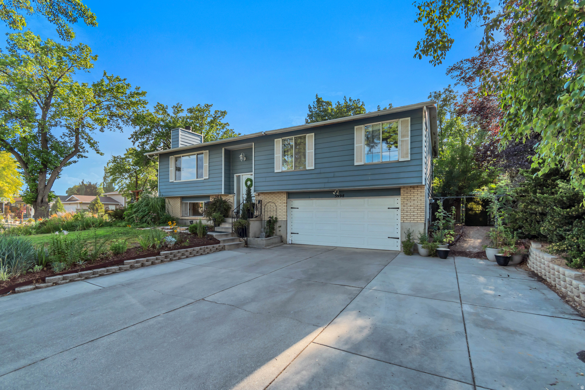 Location, Location, Location! Nestled on Blue Stone Circle in Murray, this charming blue home puts you just 3 blocks from Willow Ponds Park with soccer fields and its stocked fishing pond. Enjoy easy walking or biking access to the Jordan River Trail. Murray Golf Course is a quick drive away, and commuters will love the easy access to I-15 and I-215 - plus you're only 5 minutes from IHC and Costco. Inside, you'll find:  4 bedrooms and 2.5 bathrooms, two family rooms - one with a real wood-burning fireplace, the lower level with a cozy gas fireplace, rich oak hardwood and slate flooring throughout the main living areas, new carpet in the upstairs bedrooms, recessed lighting, crown molding, and custom built-ins, three new kitchen appliances, surround sound in both the living room and garage. Outside is where this home truly shines: Enjoy a stunning perennial garden perfect for cutting your own bouquets. Garden lovers will appreciate the spacious shed and raised-container veggie beds tucked in the side yard, along with secret alcoves perfect for kids' adventures or quiet lounging.  Entertain in style on the expansive 20x24 lower deck, or relax on the brand-new deck boards on 16x12 upper deck just off the kitchen. The oversized 2 car garage is a hobbyist's dream. This house has a new roof, covered gutters, and space for RV parking, this home is as practical as it is charming. Move-in ready and full of character - all it needs now is you!