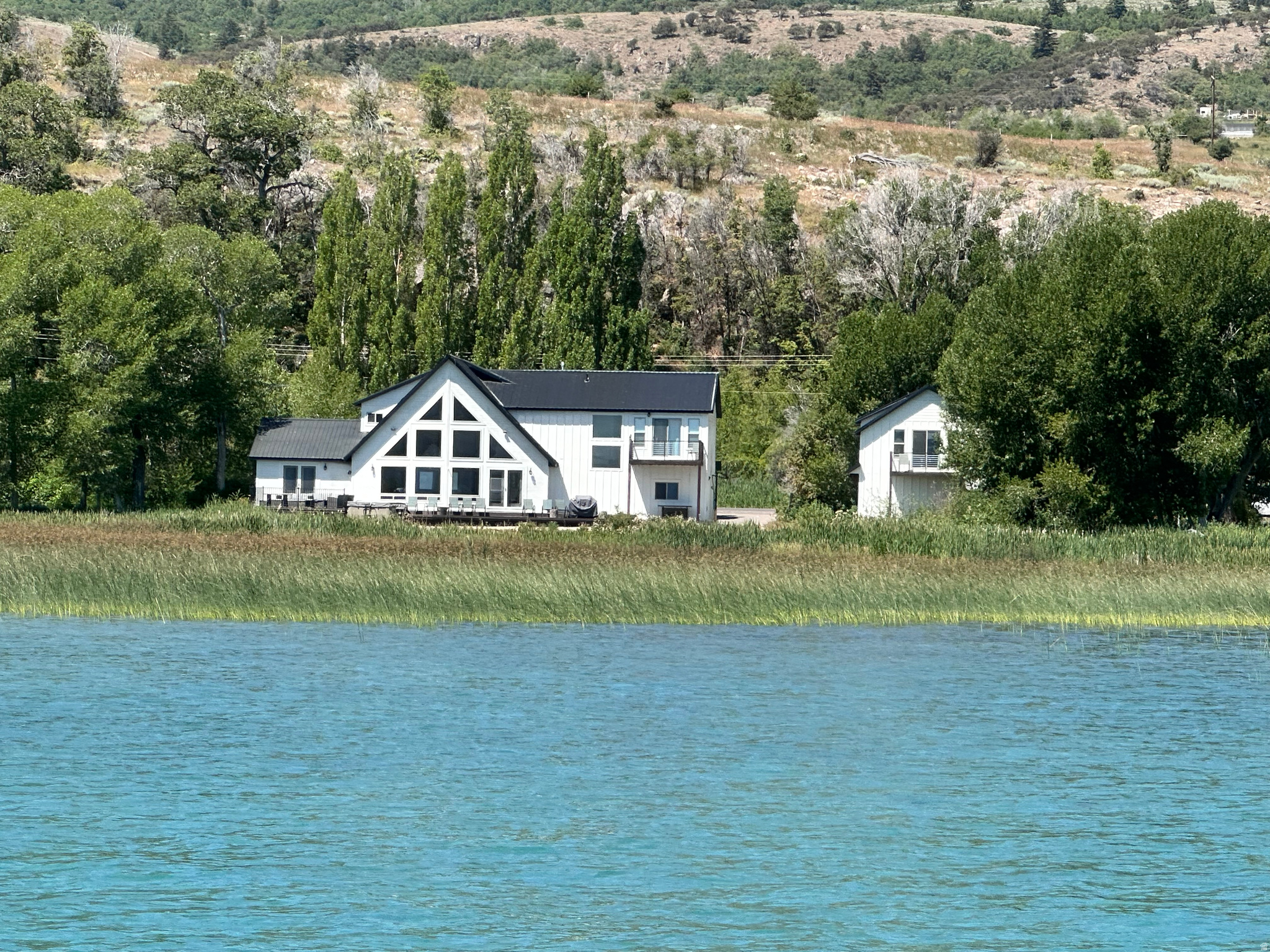 Huge Price Drop! Ready for your own summer getaway & rental income this season! Bear Lake Beachfront Home  201 ft of lakefront & your own private slice of paradise. This is an incredible opportunity for a dream vacation home or investment property, already set up & operating as a short-term rental. The main home offers 5 bedrooms & 4 bathrooms, breathtaking panoramic lake views, a spacious kitchen, comfortable family room, & a large deck with a hot tub overlooking the lake. The detached garage adds even more flexibility with a large bunk room and full bath-perfect for guests, kids, or extra privacy. With a major price reduction, this is the perfect time to secure your own piece of Bear Lake & start enjoying both personal use and rental income right away.