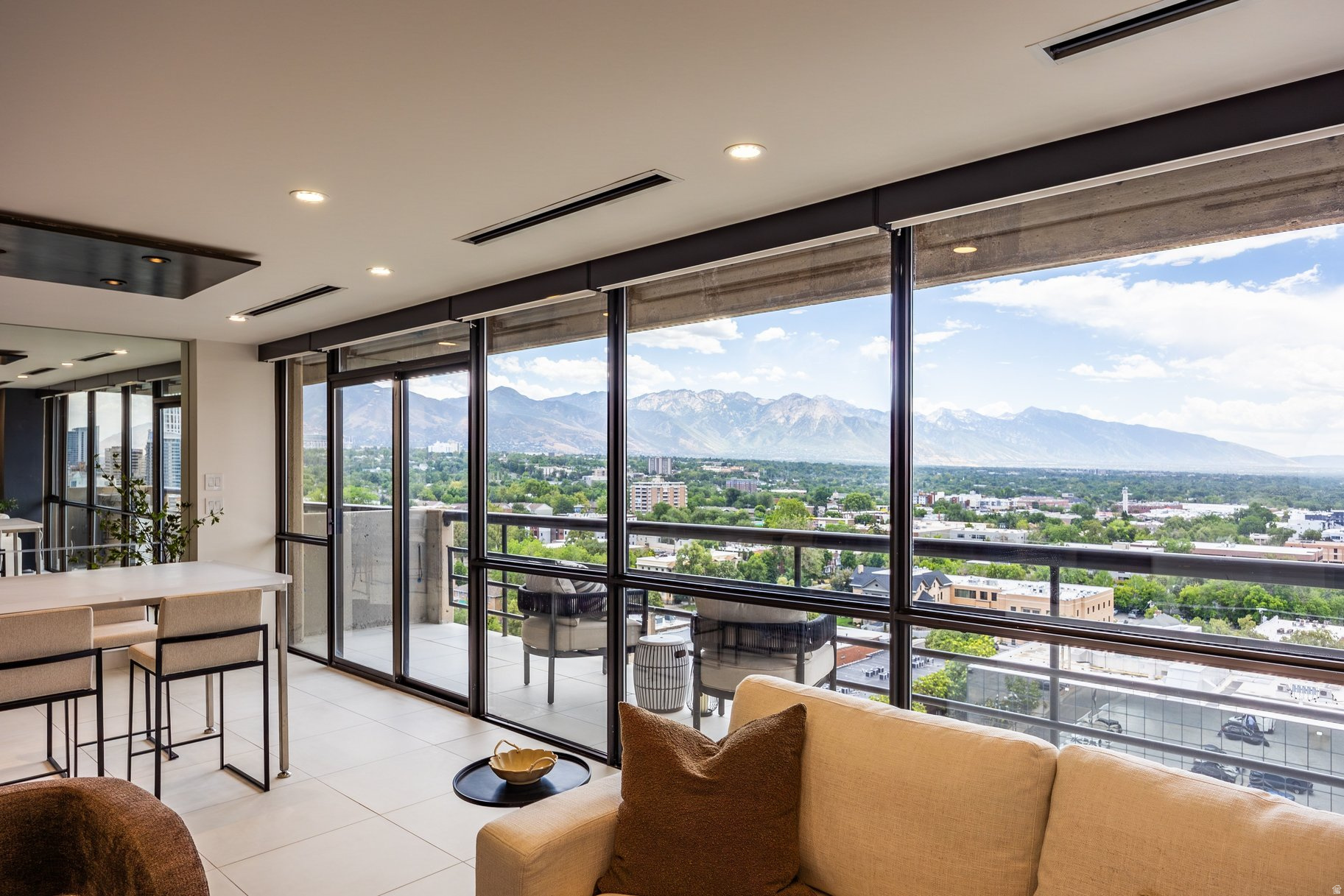 For elevated city living in the heart of Salt Lake, few opportunities compare to this southwest corner pied--terre on the tenth floor of Governors Plaza. Taken to the studs and rebuilt corner to corner, the residence was reconfigured to be a one of one penthouse style residence. Perched above Historic South Temple, with two private terraces the home looks south to the Wasatch Range, the U of U, and west to downtown stretching out to the lake.  Inside, the feeling is bright and modern, filled with natural light across white tile floors, custom espresso colored cabinetry, and an open layout that makes the space feel warm and inviting. The kitchen is built with highly customized storage and integrated appliances, a paneled Sub Zero fridge and a suite of Wolf appliances include an inset induction range, wall mounted oven, and steam oven. The island spreads wide into a raised bar and extends into a custom 3form dining table. The walk-in pantry has large amounts of storage, and a wet bar with a filtration system. Along the hall custom cabinetry and flush mount doors hide the utilities as well as a full bathroom. The second bedroom is anchored by dual built-in desks and custom shelving, ready to serve as a guest room when needed.  The primary suite is a world of its own, opening to a private terrace with views of downtown, the Great Salt Lake, and the Capitol. Its walk-in closet is its own room, centered around an island of drawers beneath windows that frame the mountains. The primary bath has a large double vanity with intelligent storage solutions, a marble shower with dual heads, private toilet room, and en-suite laundry.  Behind the finishes, the home is as well equipped as it is beautiful: central vacuum, heated floors, soft water, whole-home humidification, built in speaker system, and a newer furnace, air conditioning, and water heater, for comfort and low maintenance from day one. This unit enjoys 2 assigned parking spaces, dedicated storage, an indoor pool, spa, gym, and community spaces.  Living at Governors Plaza places you steps from the Avenues, downtown, and the University of Utah, with easy access to I-80 for the airport and the canyons - a rare address along historic South Temple.