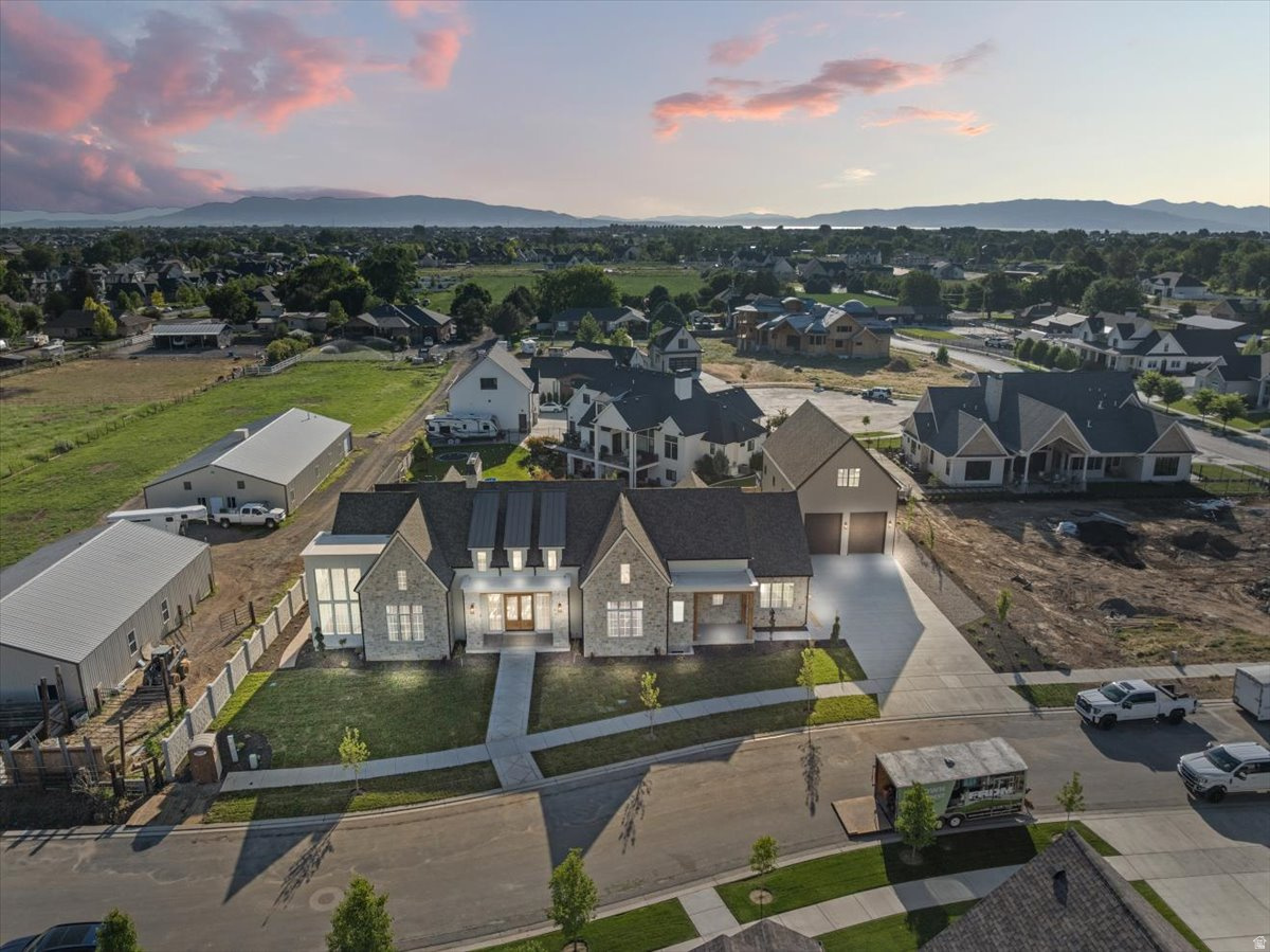 Previously featured as a Parade of Homes masterpiece, this custom home is the kind of property that stops you the moment you walk through the door and doesn't let go. Fourteen-foot ceilings draw your eye upward while floor-to-ceiling windows pull the mountain views inside, making the landscape feel like part of the architecture itself. Every finish was chosen with intention: hand-selected marble countertops, rich wood beams, engineered hardwood underfoot, designer lighting, elegant wainscoting, and striking stone fireplaces that anchor each space with warmth and weight. This is the level of craftsmanship you feel before you even notice the details. The floor plan was built for a life well-lived. A private movie theater, dedicated home gym, and spacious playroom mean every member of the household has a space that was designed with them in mind. The detached garage with loft and private guest entry adds a layer of versatility that most custom homes simply don't offer. Outside, the backyard reads less like a yard and more like a private resort. A pickleball court, putting green, lush landscaping, and a pool house already positioned for a future pool create an outdoor environment that rivals anything you'd find at a five-star retreat. And directly across from the lake, where the current owners spend their evenings with neighbors, the setting delivers something no finish or fixture can replicate: a genuine sense of place. Homes like this are not built twice. This is a once-in-a-generation opportunity to own something truly irreplaceable.