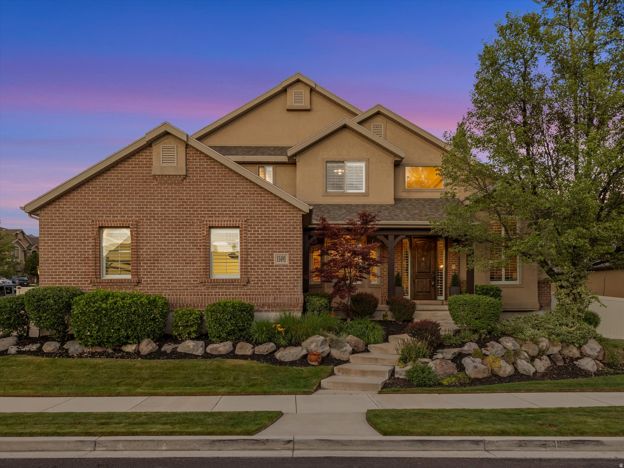 Luxurious two-story home in a prestigious East Sandy neighborhood featuring an elegant exterior with a side-load garage, welcoming front porch, and exceptional curb appeal. Perfectly positioned near top-rated schools, parks, shopping, dining, world-class skiing, and outdoor recreation in Little Cottonwood Canyon. This home offers an unmatched lifestyle in one of the area's most desirable locations. Inside, a breathtaking two-story entryway greets you, showcasing a grand staircase with custom wood and iron railing. Just off the entry, the sophisticated living room is enhanced with a stylish dimensional accent wall, creating the perfect space for entertaining or relaxing. The inviting great room features a beautiful shiplap accent wall and a cozy gas fireplace, seamlessly connecting to the showstopping gourmet kitchen. Thoughtfully updated, the kitchen boasts new white cabinetry, quartz countertops, designer tile backsplash, pendant lighting, stainless steel appliances, double ovens, gas range with wood-clad hood, built-in refrigerator, spacious center island, pantry, and a convenient built-in water bottle filler. From the kitchen, step outside to the covered patio and the beautifully landscaped backyard. The main floor also includes a formal dining room, a private den ideal for a home office, and a half bath for guests. Recent upgrades include two new water heaters, luxury vinyl plank flooring, fresh paint, plantation shutters, and newer carpet. Upstairs, you will find four spacious bedrooms and two full bathrooms, including the luxurious primary suite complete with an organized walk-in closet and spa-inspired bathroom featuring a double vanity, a jetted soaking tub, and separate shower. The lower level offers an additional bedroom and a well-appointed three-quarter bathroom. There is also space to grow by adding bedrooms, a home gym, a theater, or a recreation room. Outside, the backyard is a private park-like retreat featuring lush lawn areas, mature landscaping, stone accents, manicured plants, a sprinkler system, privacy fencing, and RV parking. This exceptional property combines luxury, comfort, thoughtful upgrades, and an unbeatable location. Don't miss this rare opportunity to enjoy the very best of Utah living.