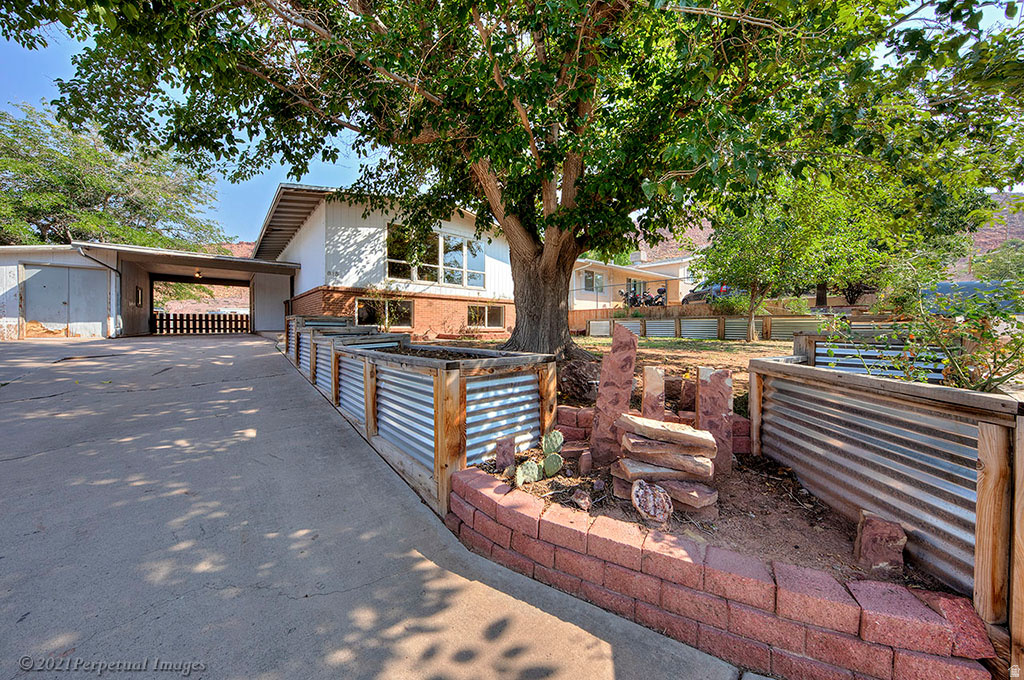 Convenient in town location - close to the ball fields, downtown, the Moab Arts and Recreation Center, the library and more. Upstairs boasts plenty of living space with an updated and open kitchen, dining area with a walkout to the large deck.  Oversized windows in the living room let the light shine in. Downstairs find four bedrooms along with a full bathroom and laundry room. Covered carport, large shed, raised garden beds front and rear and additional parking are just some of the extra features this property offers.