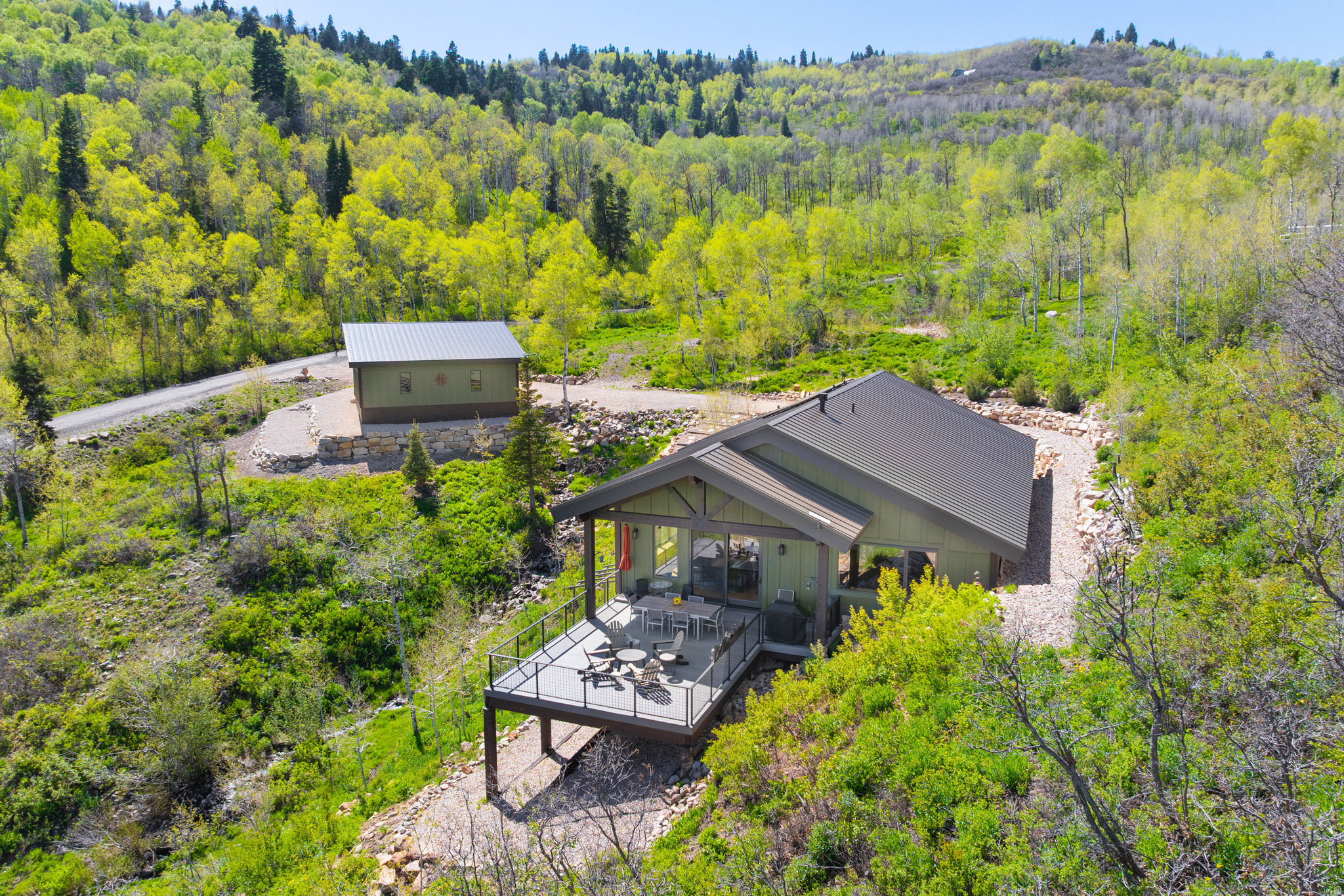 Set in a beautiful mountain setting within the gated community of Stagecoach Estates, this home combines sustainability, efficiency, and timeless design. Just minutes from Kimball Junction and within the Park City School District. 16' concrete walls keep the home cool in summer and warm through winter Paid-off solar panels - average electric bill only $12/month Propane averages $1,300 annually Generac generator for peace of mind Fire-resistant metal roof and concrete walls - low-maintenance and durable Brand-new radiant heating system Premium RO and infrared water filtration system + soft water for clean pipes and minimal soap usage Situated on 14 acres, this southeast-facing home enjoys unobstructed views, privacy, and abundant wildlife - moose, elk, deer, and wild turkeys are frequent visitors. A seasonal stream runs through the property, enhancing the mountain experience. The main level features an open-concept floor plan with vaulted ceilings, exposed beams, and solid hickory floors. Expansive windows frame sweeping canyon views, while the gas fireplace adds warmth and charm. The newly renovated gourmet kitchen flows seamlessly into the great room and out to an oversized deck, perfect for entertaining and indoor-outdoor living. The primary suite is also on the main level. Additional features include three bedrooms, three bathrooms, a dedicated office nook, and a lower-level walkout with a spacious family room. The attached garage with radiant heat is currently used as a home gym and offers excellent storage. A newly built oversized detached garage provides even more space for vehicles, gear, and toys. Enjoy true mountain living with peace, beauty, and trails right outside your door while still being just minutes from schools, shopping, and dining. The best of both worlds.
