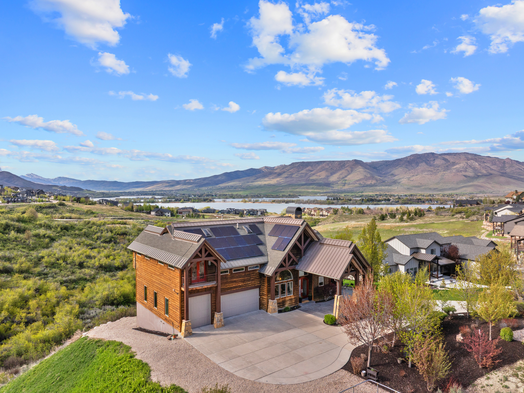 Pineview Reservoir doesn't just appear in the distance here. It fills the horizon shimmering in the morning, catching fire at dusk and it does it from nearly every room in the house.  Positioned at the quiet end of a cul-de-sac within the gated Summit at Ski Lake community, 6438 E Summit Cove sits on over an acre of private hillside with unobstructed, panoramic water and mountain views that no future development can touch. This is the lot that people in the neighborhood talk about and the home was built to honor it. Hardwood, marble, and travertine floors run throughout nearly 7,000 square feet of thoughtfully arranged living space, all designed around the main level so that daily life waking up, cooking, entertaining, unwinding happens without a single stair.  The Thermador kitchen anchors the great room with a butler's pantry, marble counters, and a floor-to-ceiling stone fireplace that draws the eye toward the reservoir beyond. A home library with floor-to-ceiling built-ins and a rolling ladder sits just off the entry a room that signals immediately this is a home built for living, not just impressing. The primary suite occupies its own wing, with a private deck, jetted soaking tub, and a wet bar a genuine retreat within the retreat.  Below, the owners' wellness level sets this property apart from anything else in the valley. A full weight room, dedicated yoga sanctuary, built-in sauna, and steam shower not amenities bolted on as an afterthought, but a professionally designed complex built around recovery and renewal. The theater room rounds out the lower level, and everything stays. Solar panels with battery storage and a remotely controlled heated driveway handle the practical demands of mountain ownership quietly in the background.  Eight minutes to Snowbasin. Minutes more to Powder Mountain and Nordic Valley. And every evening, the reservoir catches the last light of the day right outside your window. There is nothing else like this position in Summit at Ski Lake and very little like it anywhere in Ogden Valley.