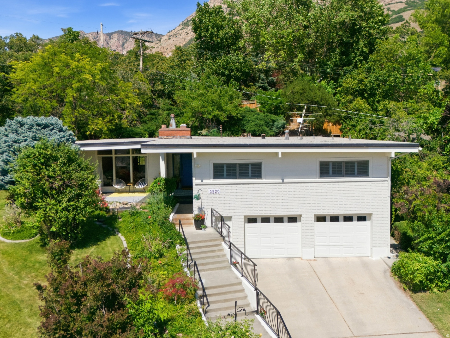 Tucked into a quiet Ogden foothill cul-de-sac, this mid-century rambler feels like a private retreat without leaving the city behind. Mature trees, mountain views, a peaceful garden pond, and wildlife sightings set the tone before you even step inside. Inside, the character is the kind buyers hope for and rarely find: hardwood floors, exposed beams, big windows, a white brick fireplace, and bright open spaces made for gathering. The main level offers 3 bedrooms, 2 bathrooms, laundry, and an enclosed porch/sunroom that may quickly become your favorite room. Downstairs adds a family room, bedroom, bath, flex/exercise space, oversized garage, and excellent storage, including an approx. 17' x 26' crawl/storage area.