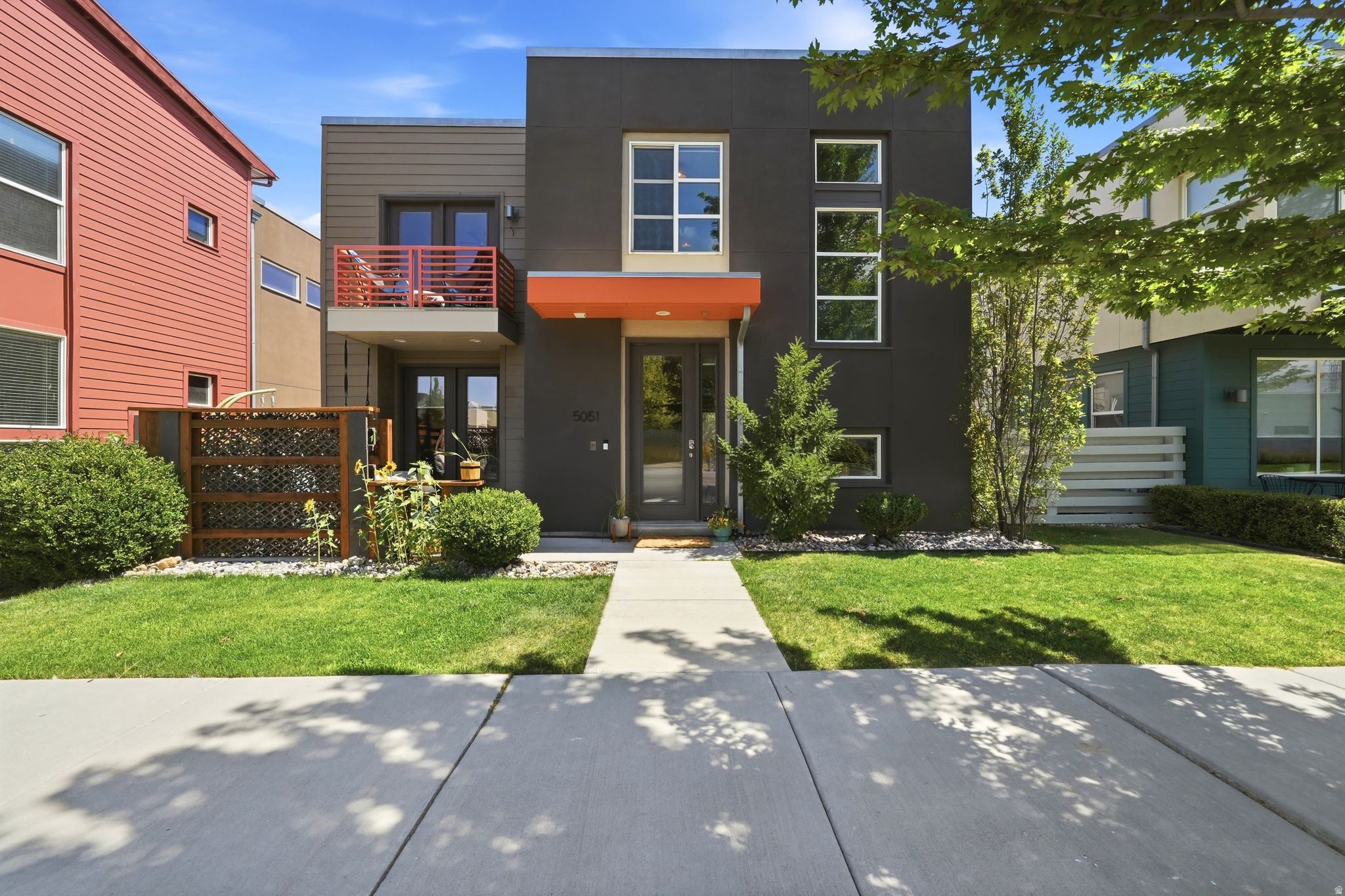 Contemporary style, flexible living space, and a fantastic Daybreak location come together in this beautifully designed home. The bright, open-concept main level features abundant natural light, modern cable stair railings, gorgeous flooring, and generous living and dining areas. The kitchen stands out with stainless steel appliances, a full tile backsplash, extensive cabinetry, and a spacious island topped with warm butcher-block countertops and bar seating. Upstairs, the primary suite includes a private balcony, while two additional bedrooms offer comfortable, versatile space. Two more bedrooms and a bathroom in the finished basement provide added flexibility for guests or a home office. The fenced courtyard offers mature trees, flagstone accents, low-maintenance landscaping, and multiple spaces to relax or entertain. An attached two-car garage provides valuable parking and storage. Enjoy Daybreak's sought-after amenities and convenient access to parks, shopping, dining, and transit. Mountain View Corridor is less than a minute away, with the Daybreak Library, TRAX station, and University of Utah Health Center approximately half a mile from home. America First Ballpark, Bangerter Highway, and The District are all within five minutes. This is contemporary Daybreak living in a location that keeps everyday conveniences close to home.