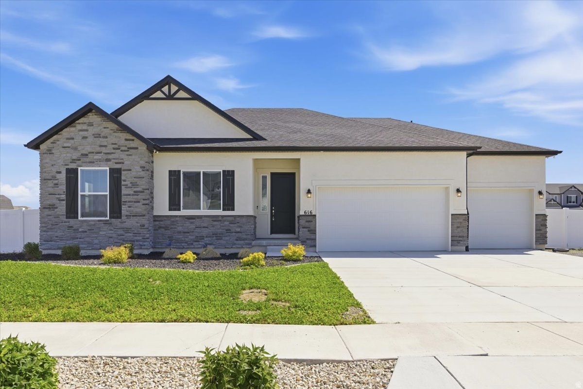 Welcome to this like-new 2022 rambler nestled on a half-acre lot in one of Grantsville's most peaceful neighborhoods, where beautiful views and quiet surroundings set the tone from the moment you arrive.  From the moment you step inside, the quality of this home is immediately apparent. The sellers spared no expense during the build, selecting upgrades throughout that elevate every room above standard new construction.  The great room is anchored by soaring tray ceilings, an abundance of natural light, and a stunning gas fireplace with a dark espresso surround and classic mantle, the perfect centerpiece for Utah winters. Rich dark LVP flooring flows seamlessly throughout the entire main level, tying together a cohesive and polished look that is as durable as it is beautiful.  The open floor plan connects the living room directly to the formal dining area and the kitchen, making this home ideal for both everyday living and entertaining. The kitchen is a true showpiece. Dark espresso shaker cabinets reach to the ceiling, providing exceptional storage, and are complemented by white quartz countertops and a full extended mosaic tile backsplash that runs the entire length of the wall. The large center island seats four comfortably and serves as the heart of the home. Appliances include a stainless steel built-in double wall oven, a separate induction cooktop, a wall-mounted stainless range hood, and a French door refrigerator. A generous walk-in pantry rounds out a kitchen that truly has it all.  One of the most clever upgrades in the home is a dedicated central vacuum inlet installed beneath a kitchen cabinet, allowing you to simply sweep debris directly into the wall without ever pulling out a hose. Small detail, big quality of life.  The open stair railing with dark wood spindles adds an architectural touch that opens up the sightlines between the main level and the basement below, giving the home a custom, elevated feel.  The oversized garage accommodates up to four vehicles and has been fully upgraded for the hobbyist or serious craftsman, with ten additional outlets installed for woodworking and workshop use, plus a 240V circuit ready for a welder, compressor, or future EV charger.  The owned solar panel system with backup battery transfers free and clear, and this is not your average solar setup. The panels keep the battery fully charged first, with any surplus energy sent back to the grid for a bill credit. When the grid goes down, the battery automatically keeps essential circuits running including the refrigerator, freezer, microwave, kitchen lights, and internet. The system is also configured so the grid cannot draw from your battery, meaning the power stays right where it belongs, in your home.  The front lawn features an intentional clover ground cover, a smart and increasingly popular alternative to traditional grass that is especially well suited for Utah's dry climate. Clover stays green with far less water than conventional turf, requires little to no mowing, and needs no fertilizer since it naturally fixes nitrogen in the soil. The backyard is partially landscaped and features a shade tree, three fruit trees, and raised garden boxes, with plenty of room to customize and grow on this spacious half-acre.  And then there is the basement. At a full 2,393 sq ft, this is not a typical unfinished space. It is a blank canvas of rare size with serious income potential. Comparable finished basement units in Grantsville are currently renting between $1,675 and $1,850 per month. Whether you are looking to offset your mortgage, create a long-term rental, or build out a mother-in-law suite, the numbers make a compelling case. We also have a trusted network of contractors available to help you finish the space to your specifications, making the path from potential to income as straightforward as possible.