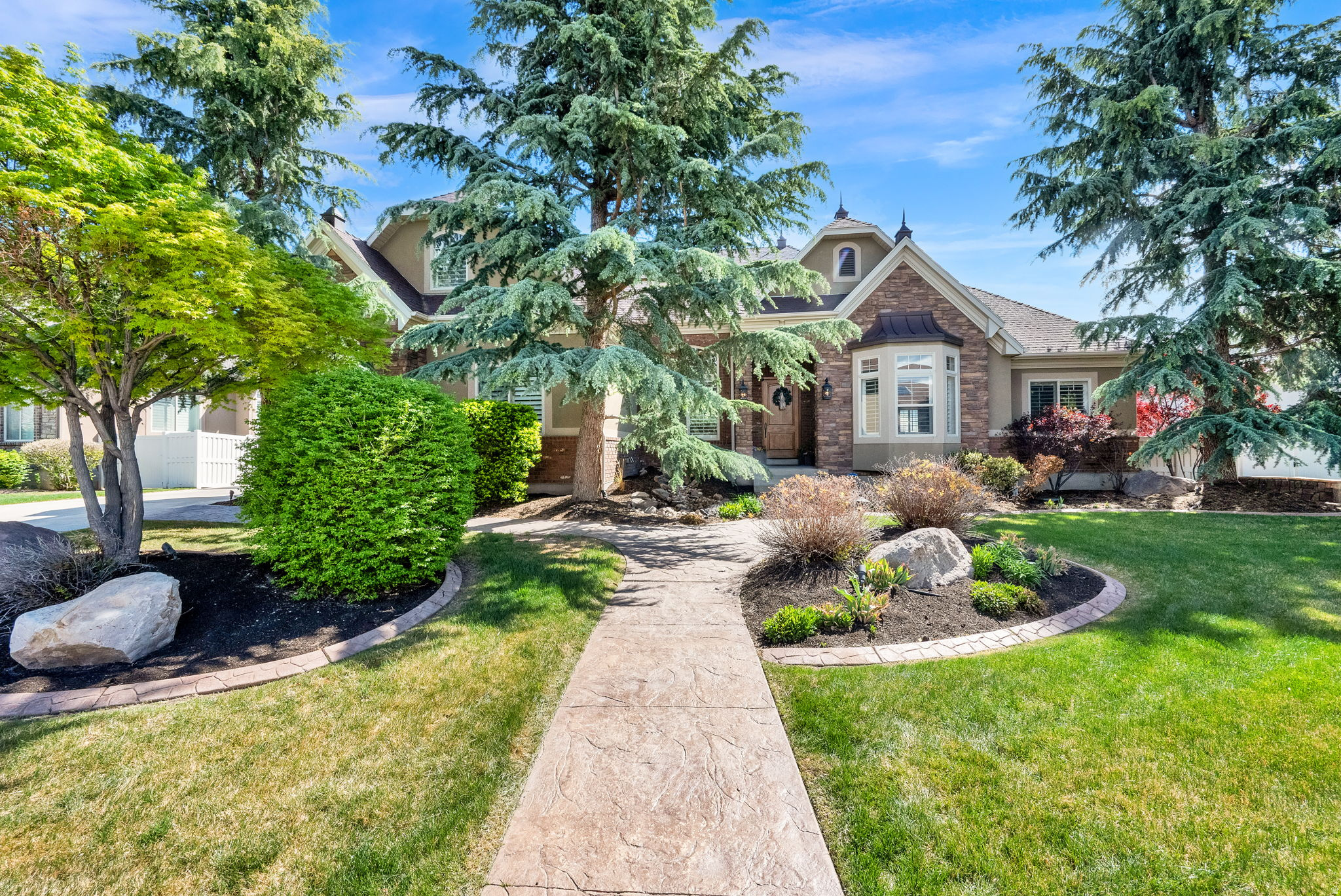 This stunning, immaculately maintained home tucked away on a quiet street offers an incredible amount of space, comfort, and flexibility. With 8 bedrooms and 5.5 bathrooms, there's room for just about anything you need, along with two full kitchens, multiple living areas, steam generator in the basement shower, a walk-out basement, and plenty of storage throughout. The oversized 4-car garage, including a tandem stall, gives you even more options for parking, hobbies, or extra space. The yard really sets this home apart. Sitting on nearly half an acre, it feels like your own private park with beautiful mountain views. There's a fenced garden area, a concrete pad with a basketball hoop (that could easily be used for pickleball), an in-ground trampoline, and a nicely finished gas fire pit with pavers. Even with all of that, there's still room to make it your own, like adding a pool. Amazing properties like this don't come around often. Schedule a showing and see it for yourself. Buyer to verify all MLS information, including square footage. Agent related to seller.