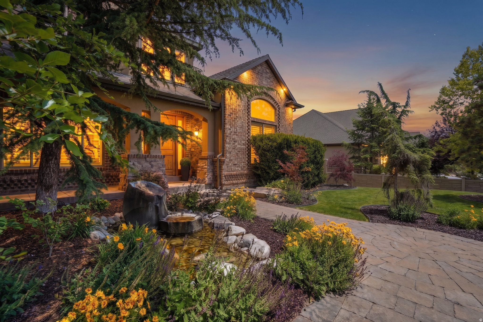 Exceptional two-story home with dual kitchens, ideal for multi-generational living, a walk-out basement with ADU potential, rare suspended garages featuring a private theater room and dedicated exercise room below, and a spectacular park-like backyard designed for entertaining and relaxation. Generous room sizes, three family rooms, and a versatile formal living room provide incredible flexibility for a home office, music room, conservatory, or elegant sitting area. Both beautifully appointed kitchens feature granite countertops, double ovens, and a spacious walk-in pantry, making entertaining effortless. The luxurious primary suite offers a spa-like retreat with a soaking tub, separate shower, dual vanities, a private water closet, and an oversized walk-in closet. Step outside to your own private backyard oasis. Professionally designed landscaping creates a peaceful, resort-style setting with an expansive upper patio for outdoor dining, stone steps leading to a secluded lower patio, a tranquil cascading waterfall, and a custom firepit with built-in stone seating surrounded by mature trees. This truly one-of-a-kind property offers an exceptional combination of flexible living space, timeless design, and unforgettable indoor and outdoor amenities.