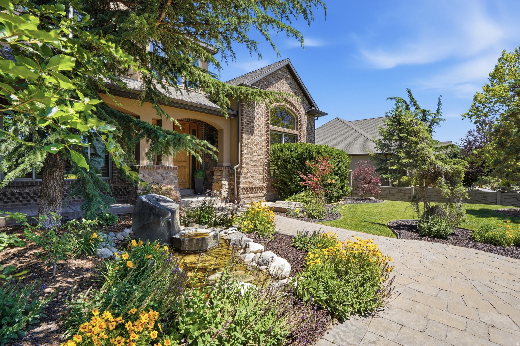 Coming Soon! This stunning 2-story Tuscan-style home offers an exceptional floor plan with generous room sizes throughout. The versatile formal living room is perfect as a home office, conservatory, or formal sitting area. Three family rooms provide plenty of space for everyone. Two beautifully appointed kitchens feature granite countertops and double ovens, plus a walk-in pantry for ample storage. The primary suite is a true retreat with a separate tub and shower, double-sink vanity, private water closet, and an oversized walk-in closet. Unique suspended garages house a dedicated exercise room and a private theater room beneath them - a rare and impressive feature. Outside, the professionally landscaped yard is an absolute showstopper. Relax around the fire pit with stone seating nestled beneath a canopy of mature trees, enjoy the covered patio, or unwind on the lower patio surrounded by lush plantings, rock steps, and a beautiful water feature. This is a one-of-a-kind property that truly has it all.