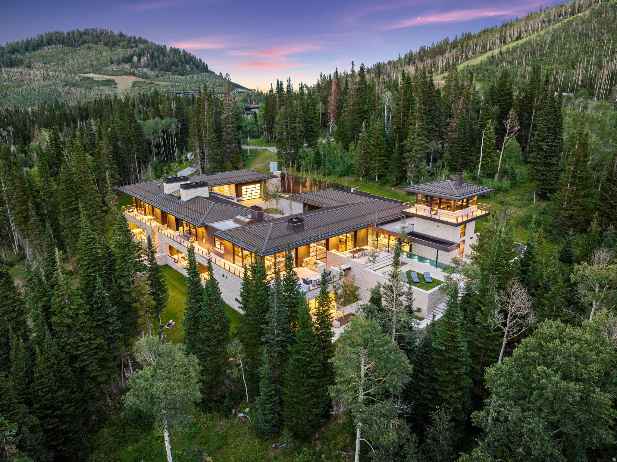 Monitor's Rest, winner of Robb Report's Best of the Best award for Best Amenities, stands on five ski-in, ski-out acres in The Colony at White Pine Canyon, framed by the dramatic rise of Monitor Bowl. The setting cannot be engineered or repeated. The residence itself is the work of Iluminus Group, CLB Architects, Design Workshop, Delos, Orsman Design, and Magleby Estate Homes, the product of years of design and construction. Nearly 18,000 square feet are built from materials chosen to outlive their owners: a full copper roof already taking its patina, Croatian limestone, shou sugi ban charred cypress, Italian thermally broken steel at every window and door. Winter is a private matter. From the ski lounge and activities garage, your own ski beach puts you directly onto Park City Mountain, the Quicksilver Gondola close at hand, on snow while the public is still scraping windshields. When the snow leaves, the property gets better: a Design Workshop landscape of lawns, water and fire features, granite boulders, and wraparound terraces that increase the living area when the glass walls retract, with 75-degree afternoons and trail access from the same door that releases skiers in January. The 60-foot stainless steel pool begins indoors and finishes in open air. The rarest amenities here are sleep, recovery, and time. Delos' DARWIN Home Wellness System calibrates circadian lighting, air, and water around the clock. The owner's suite is oxygen-regulated, with an executive office, library, and a bath that operates as a private spa. The wellness wing holds a gym, Himalayan salt massage room with oxygen system, hammam, cold plunge, infrared sauna, and hot tub. It hosts at the scale of a private resort without feeling like one: a Marrone of Italy kitchen with WoodStone pizza oven, club room with full bar and floating fireplace, cinema with Steinway Lyngdorf audio and 200-inch Barco 4K laser projection, bowling alley, golf simulator, indoor sports court with climbing wall, an eight-queen bunk room for grandchildren by the roomful, and an attached lockout guesthouse with its own front door for staff or long-stay guests. Above it all, a panoramic tower rises over the treetops with views no neighbor shares. Historic Main Street is 15 minutes away, Salt Lake City International 35 minutes, Heber Valley's G650-capable runway 30 minutes. Land in the morning, be on the mountain by noon.