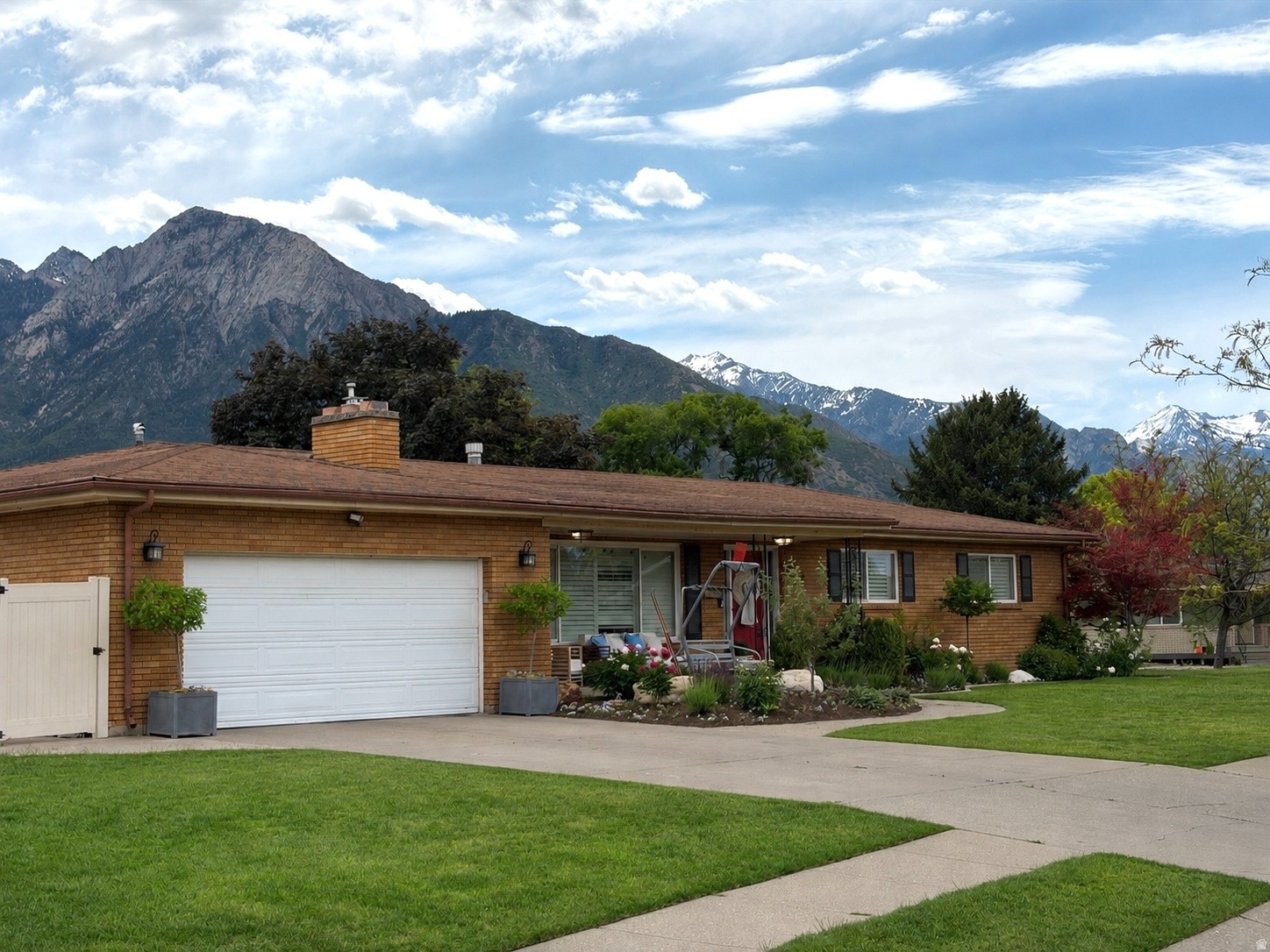 BEAUTIFUL RAMBLER! MILLCREEK NEIGHBORHOOD!! STUNNING MOUNTAIN VIEWS! This classic brick home is situated in a highly desirable neighborhood with amazing schools. This home offers timeless curb appeal with mature landscaping, colorful garden beds, and a welcoming covered front porch. The spacious front yard and wide driveway with 2 car garage provide excellent functionality. Inside, you'll find comfortable single-level living with a thoughtful layout designed for both everyday life and entertaining. Primary bedroom on the main level with ensuite bathroom. Large front windows fill the home with natural light, and the established landscaping creates a peaceful setting with privacy and beauty. Basement entrance that you could turn the basement into a Mother in law ADU. Convient location for dinning and shopping. Located in a quiet, well-kept neighborhood, this home combines classic charm with unbeatable views of the Mountains. This property offers the perfect place to call home.