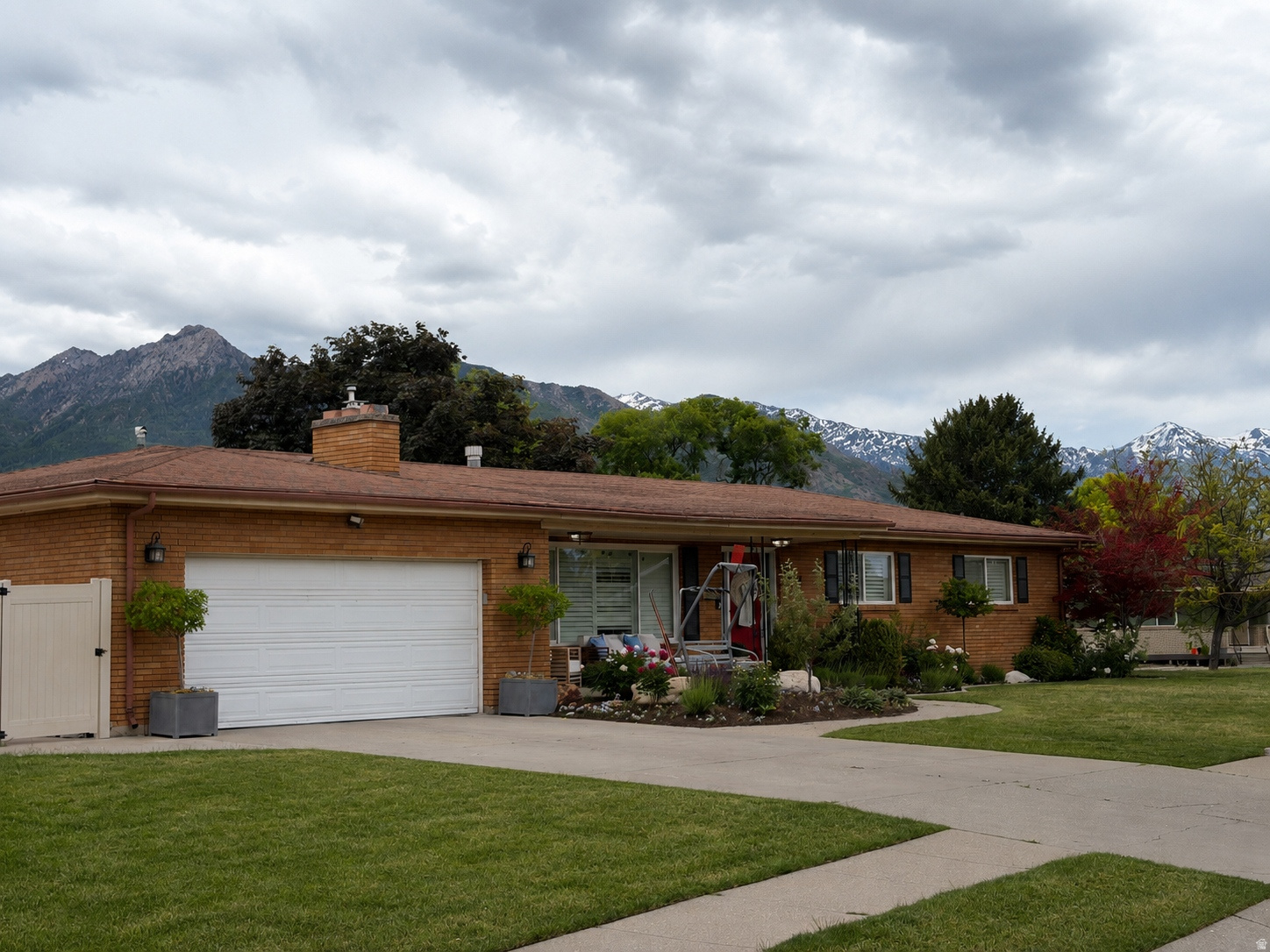 BEAUTIFUL RAMBLER! MILLCREEK NEIGHBORHOOD!! STUNNING MOUNTAIN VIEWS! This classic brick home is situated in a highly desirable neighborhood with amazing schools. This home offers timeless curb appeal with mature landscaping, colorful garden beds, and a welcoming covered front porch. The spacious front yard and wide driveway with 2 car garage provide excellent functionality. Inside, you'll find comfortable single-level living with a thoughtful layout designed for both everyday life and entertaining. Primary bedroom on the main level with ensuite bathroom. Large front windows fill the home with natural light, and the established landscaping creates a peaceful setting with privacy and beauty. Basement entrance that you could turn the basement into a Mother in law ADU. Convient location for dinning and shopping. Located in a quiet, well-kept neighborhood, this home combines classic charm with unbeatable views of the Mountains. This property offers the perfect place to call home.