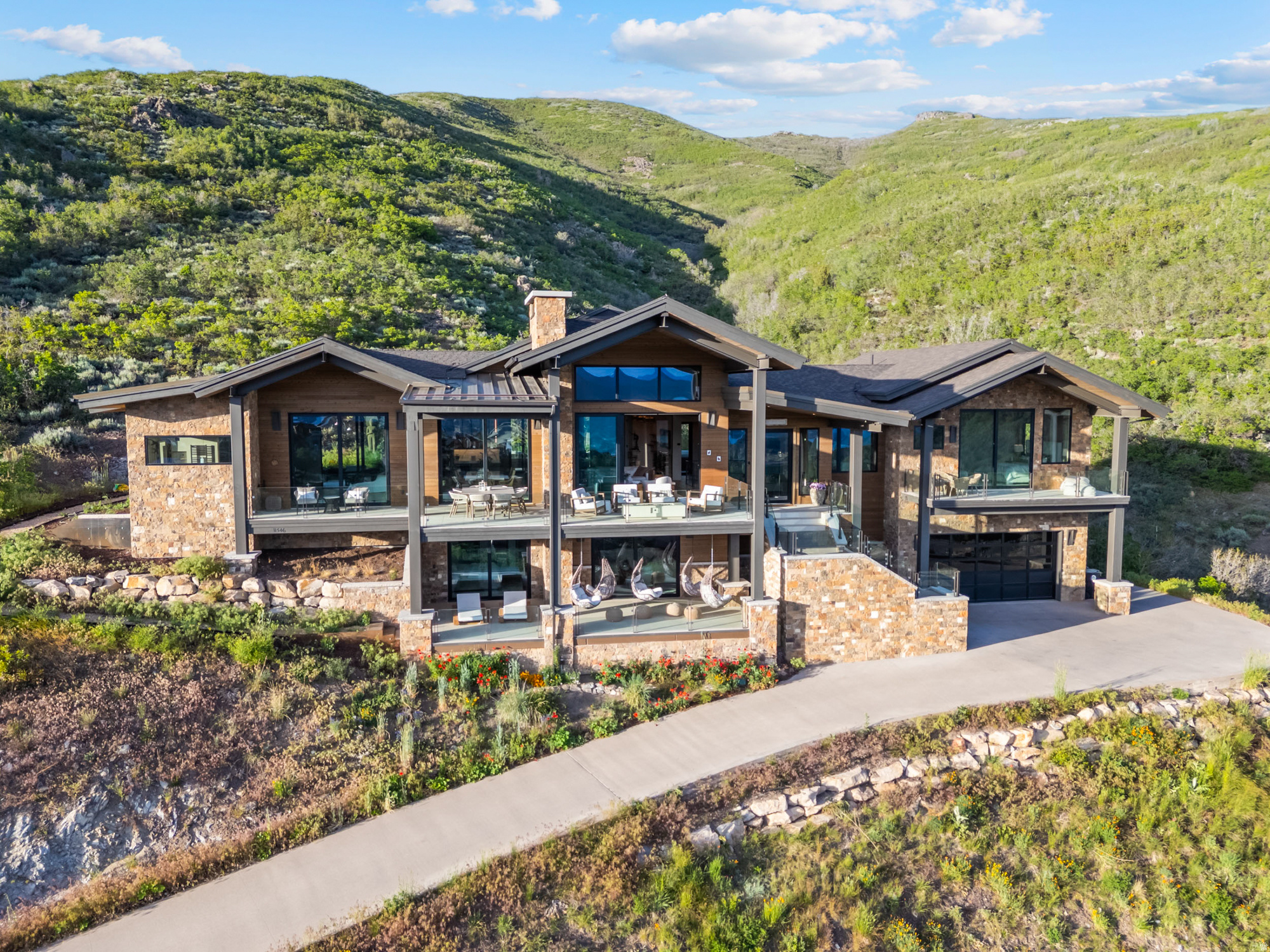 Welcome to one of the most breathtaking view retreat properties overlooking Park City. Enjoy panoramic views of Deer Valley, Lake Jordanelle, and Mount Timpanogos.  This 5,116-square-foot residence offers rare privacy and year-round beauty. Featuring 4 bedrooms, each with a private ensuite, plus an office. Situated on a private cul-de-sac and backing to hundreds of acres of open space.  Summer living shines here with multiple outdoor spaces designed for relaxation and connection. Unwind in the sunken hot tub overlooking the ravine, enjoy the sauna, gather on expansive patios, or explore trails just beyond your backyard.  The home moves in rhythm with nature. Morning light fills the open living area while expansive windows frame breathtaking western sunsets. A striking limestone fireplace anchors the main living space, complemented by crystal double countertops, wood-clad ceilings, and warm organic finishes throughout.  The primary suite captures both sunrise and sunset, creating a peaceful sanctuary. The spa-inspired bathroom features dual vanities, a double-headed shower with Deer Valley views, and a handcrafted European clay soaking tub. Each guest suite offers privacy, comfort, and outdoor access.  A second living area downstairs opens to a covered deck with swinging chairs and offers the perfect setting for entertaining. The space easily accommodates a dedicated mahjong or game table, creating a warm gathering place for friends and family while enjoying the home's spectacular mountain backdrop.  Throughout the home, thoughtful design details, recessed door framing, and soft limewashed walls create a sense of calm and effortless flow.  Just 10 minutes from Park City and Deer Valley East Village while 40 minutes to the Salt Lake City International airport.  Ask about the option to include a one-year ski club membership and private shuttle.