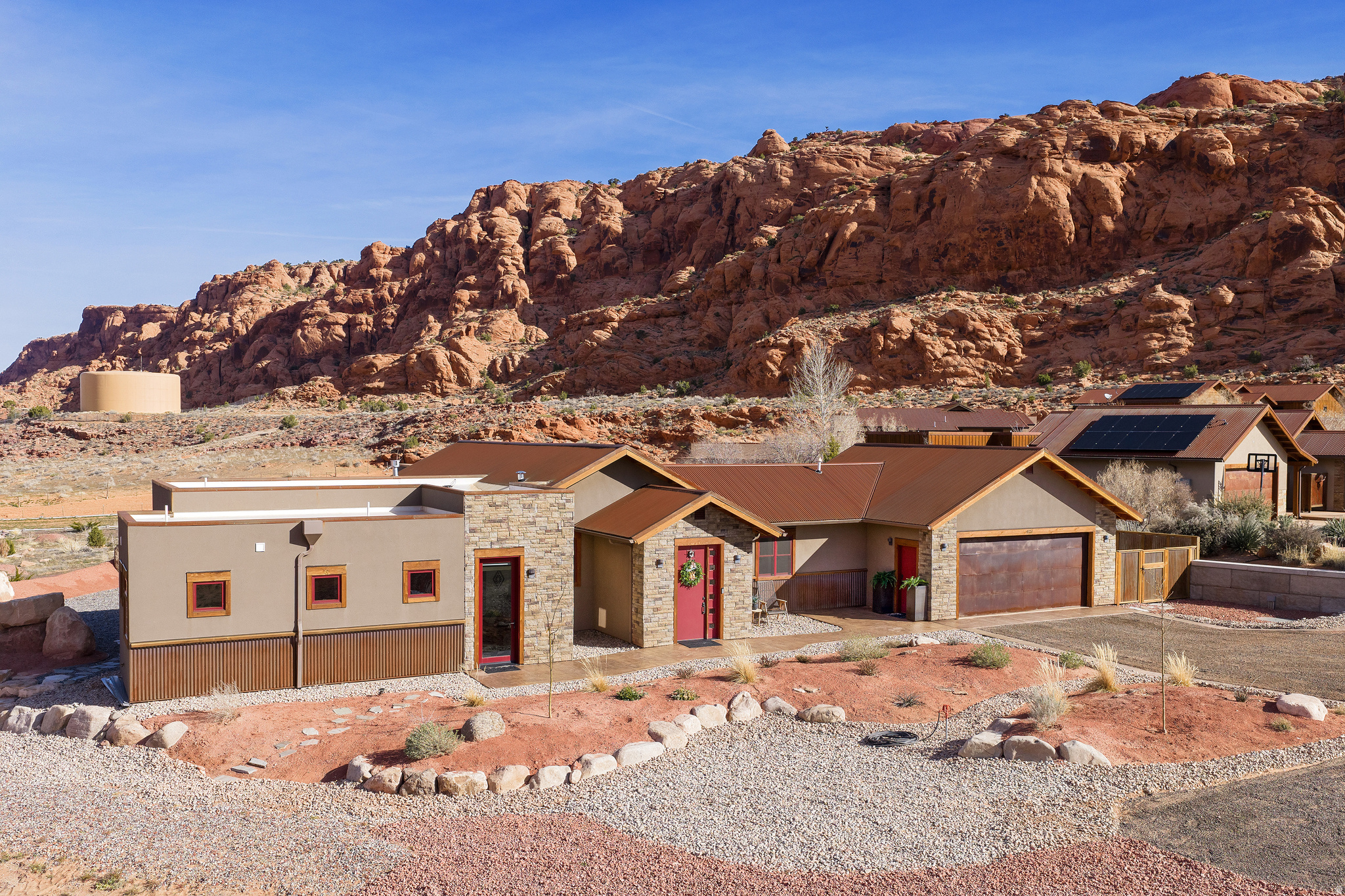DESERT LIVING AT ITS BEST in this stunning luxury home nestled among beautiful towering red rocks in MOAB, Utah. This home features elegant rustic charm with soaring Alder ceilings, a rugged floor-to-ceiling stone fireplace, knotty Alder cabinetry, and leathered quartzite countertops. The chef's kitchen offers abundant prep space, apron sink with oil-rubbed bronze faucet, double ovens (electric convection + six-burner gas range), side-by-side stainless refrigerator, massive island with pull-outs, Butler's pantry, wet bar with wine fridge and ice maker, and a built-in office area.  The light-filled living room opens seamlessly to both a private courtyard and expansive patio, creating ideal indoor-outdoor flow. The primary suite is a true retreat with automatic blinds, patio access, and a spa-inspired bath featuring a luxury walk-in shower with rain head, body sprays, and handheld sprayer-- plus plumbing for a sauna or soaking tub, with High-honed travertine countertops and vessel sinks to complete the spa feel. Three additional bedrooms feature en-suite bathrooms with stone countertops and walk-in closets and built-in shelving. The fourth bedroom includes a loft bed with additional seating or office space below. Just off the kitchen is a guest bath with walk-in tile shower, stone flooring, and honed marble countertop with chiseled edge. The laundry room and garage are conveniently adjacent, offering butcher block folding counters, a large workbench, and extra cabinet storage.  Enjoy multiple outdoor living spaces, including a private courtyard with massive stone walls, built-in hot tub, fire feature, surround sound, and bar seating. The extended stone patio includes a built-in gas firepit, massive red rocks, flagstone pathways, and is plumbed for an outdoor kitchen and BBQ. You will love the high tech features in this home including; smart thermostat, built in alarm system, front door google camera, speakers and TV that all work from your phone. All information deemed to be reliable by the listing office; buyer to verify all.