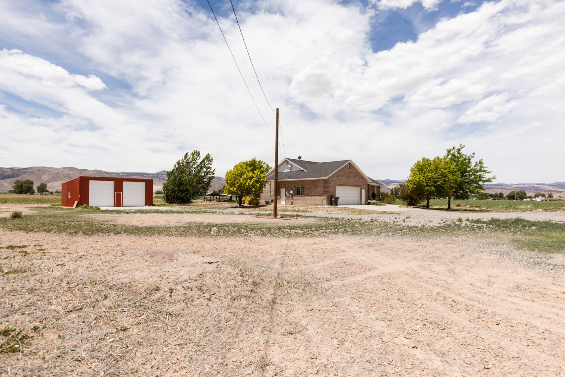 Solid brick construction on 3 open acres in Central Valley, Utah - this 6-bedroom, 3-bath home delivers 3,548 sq ft of living space with panoramic mountain and valley views in every direction. The property features a covered front porch, attached 2-car garage, and a detached red steel shop for equipment, hobbies, or serious work space. Solar panels already in place and paid off for energy efficiency. Surrounded by irrigated farmland with room to grow, graze, or simply breathe. Properties like this - brick, acreage, shop, and views - don't come available often in Sevier Valley.