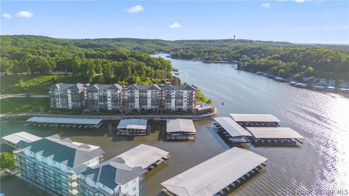 This exceptional 3-bedroom, 2.5-bath fully furnished lakefront condo offers the ultimate "turn-key" Lake of the Ozarks experience. Positioned as the original "model" unit, it boasts superior details and numerous upgrades, including crown molding with accent lighting, stainless steel appliances, and granite countertops. Some of the key condo features are elevator access that opens directly in front of  the unit. Open-concept living, dining, and kitchen area with tasteful, included furnishings. Screened-in lakeside patio equipped with high-quality matching Polywood furniture. A cozy fireplace designed with plumbing capabilities to allow an outdoor spigot for grilling. Access to three community pools. Includes a 12' x 36' boat slip. Conveniently located at the 2mm, providing quick access to restaurants, golf, and shopping. Complete your lake lifestyle with the optional, separate purchase of the seller's boat and hoist: 2015 Bennington Tritoon 25R, 250HP Mercury Outboard with only 415 hours, 10,000 lb capacity hoist already installed in the slip. This is a rare opportunity to purchase a meticulously maintained, model-level unit with top-tier amenities at the Midwest Coast.