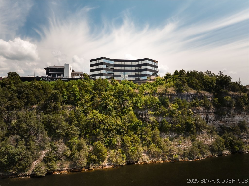 Lake of the Ozarks iconic and premier office building is for sale at Lake of the Ozarks. If you have ever been in the building you remember the view & the experience of being in the building. I have heard it many times but this one truly has some of the best views on the entire lake! Nearly 30,000 sq ft, lake frontage, hwy frontage, great parking, & an elevator, all located in the heart of Lake Ozark with easy access to the community bridge, Bagnell Dam strip & Horseshoe Bend Parkway. The building has been condominiumized and every unit except for unit 105 is included in the sale. Currently the building is completely occupied with great tenants. The possibilities with this structure are endless. Keep it as the landmark office building it is, turn part of it into a restaurant, or even create residential opportunities. The majority of the walls in the building can be removed allowing for easy transformation/redesign. The building consists of 4 floors, with each level having its own Foyer.  The building has been maintained well with recent improvements consisting of a new roof and new HVAC systems.  With this view, someone will have a vision to do something great with this building!