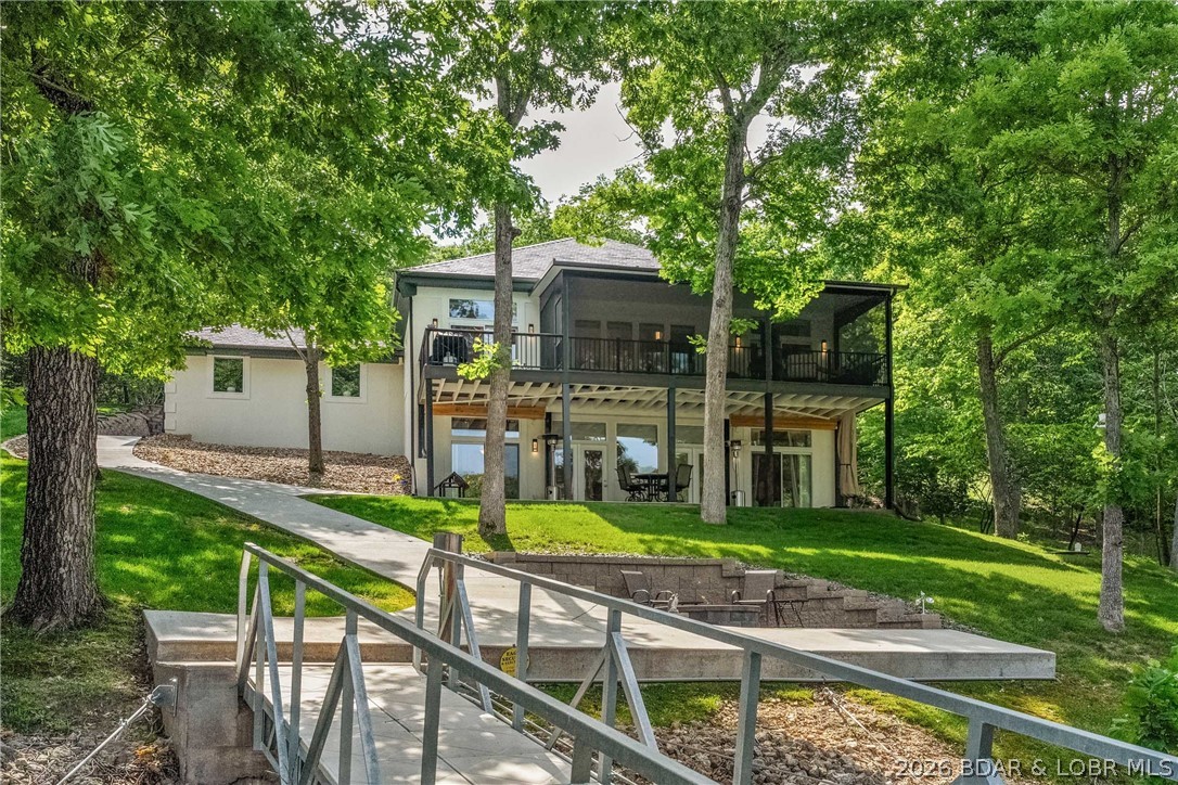 Tucked away in the prestigious Villages at Shawnee Bend, this updated lakefront home delivers the lifestyle buyers want without the maintenance & expense of a massive estate. Situated on a double lot with 190 ft of protected shoreline, this property offers privacy, calm water, & a setting that is hard to match at this price point in this community. With nearly 3,000 sq ft, the home features 3 spacious suites plus an office large enough to function as a 4th sleeping area. The main level primary suite is a retreat with a spa-inspired bath, while the lower level suites offer excellent space & access to lakeside patio. Extensive recent improvements include paint, a DaVinci roof, flooring, fixtures, appliances, vanity tops, a gorgeous fireplace with herringbone tile surround, screened porch addition, new driveway, golf cart path, firepit area, and a premium custom concrete dock complete with a 12x32 slip, shallow water boat lift, & swim platform. The lakeside setting is exceptional, private yet still offering water depth suitable for larger boats. Homes in The Villages at Shawnee Bend rarely offer this combination to enjoy luxury lake living without the price of the mega-estates nearby.