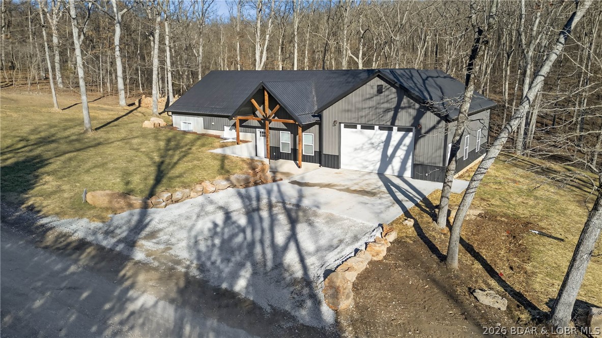 New construction 3-bedroom, 2-bath home situated on 4.66± acres with access to the Lake of the Ozarks. This property offers a spacious open-concept living area ideal for everyday living and entertaining. The kitchen features a large center island, ample cabinetry, and a pantry. All bedrooms are generously sized, with the primary suite offering an ensuite bath and a large walk-in closet. A sizable 35 x 25 attached shop provides excellent space for storage, hobbies, or workspace needs. Enjoy peaceful views of the surrounding acreage from the back porch. The home is finished with durable metal siding and a metal roof, along with laminate and carpet flooring throughout.