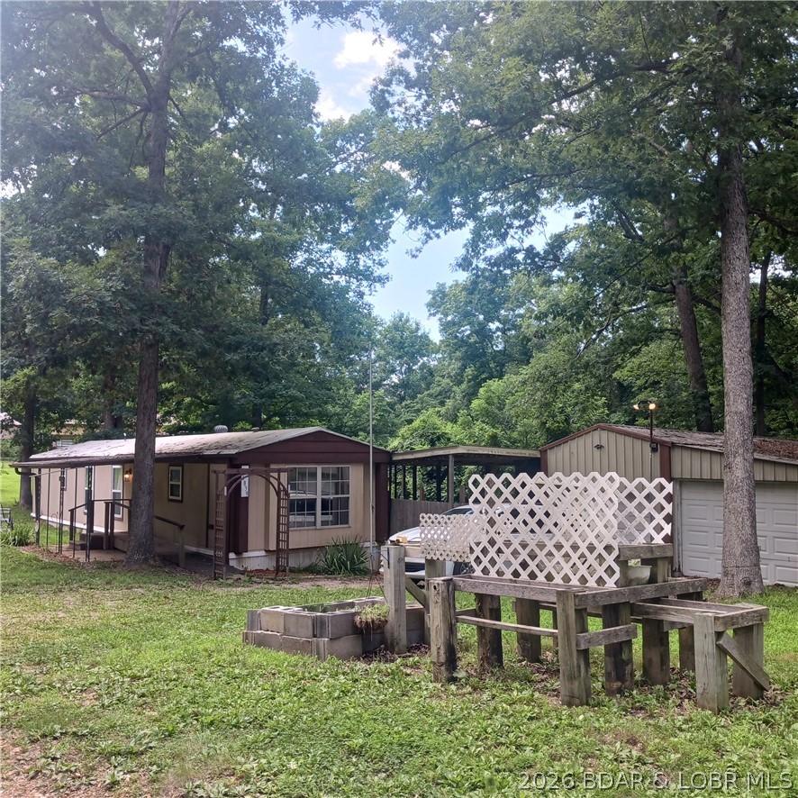 Newly remodeled, updated 2nd-tier vacation rental or year-round home within walking distance of the 54,000-acre Lake of the Ozarks; only 1 mi. from a Marina & dock rentals, and only a few miles from the Wigwam School boat launch pad & fishing area. This single-wide mobile home features a newer HVAC/water heater, luxury vinyl floors & freshly painted walls throughout (All done within the last 4 years); updated kitchen/dining area with island, breakfast bar, new kitchen appliances, combo washer/dryer, 2 bedrooms, one bath w/large tub and bidet, covered front walkway & wheelchair-accessible front-entrance, and a covered back patio for outdoor grilling and entertaining. Out-buildings include a detached 672 sq. ft. double-car garage with electronic-switch door opener, plus a 96- sq. ft. (built on site) storage shed and covered concrete walkway from the back door to the storage shed and garage. There is also a workshop and storage area (w/electricity), a previously-built raised garden & also a chicken coop for folks who envision raising their own chickens, eggs, and vegetables. As an additional bonus (with a strong offer), owners will include a low-mileage bass boat, motor & trailer.