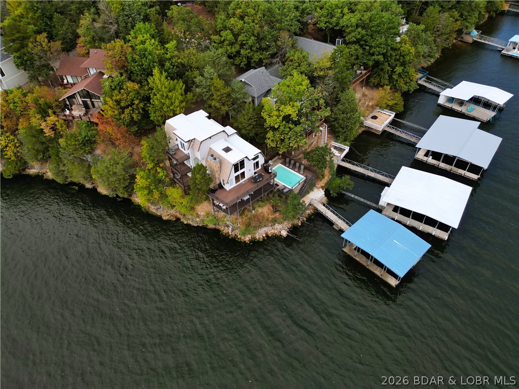 $25K CREDIT at closing toward replacements of your choice, flooring, carpet, painting, closing costs or ANY other changes you would want, the seller will write you a check at closing!  Make this home your next home away from home OR rental investment.  Make Lake memories happen in this beautifully situated 5-bedroom, 4.5-bath home located in Tan-Tar-A Estates and the well known Margaretville at the 26-mile marker—and best of all, there is NO Land Lease.  This home is turn-key, has been nicely decorated and comes ready for immediate enjoyment.  Trek decking, balconies off three of the bdrms and wrap around decks overlooking all angles of the Lake.  A 6' deep rectangular concrete swimming pool, parking for up to five vehicles, and the stunning sunsets and Lake views are free!  Floor to ceiling windows, updated Kitchen and a cozy fireplace.  With a proven VRBO rental history available for qualified buyers this motivated seller make Margaritaville your wants to make this home your next Lake designation.  Bring all reasonable offers, it's very easy access showings day or early evenings.  Check it out, don't miss out on saving money!