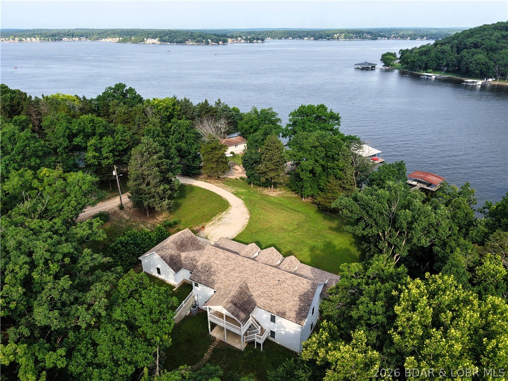 Lakefront Oasis! Discover this exceptional 5,200+ sq ft custom built home offering 190'+- of pristine lakefront on 12.3 private acres. Featuring 4 spacious primary suites, each with a private bath, this home provides comfort & privacy for family and guests. His & Hers Walkin closets in the larger first floor primary.   The open-concept living, dining, & kitchen area creates the perfect space for entertaining. Enjoy the roomy game/family room with bath for guests, abundant storage, and multiple gathering areas throughout the home. Relax outdoors on the covered deck and covered patio overlooking the peaceful woods, or the covered lakeside porch while taking in the beauty of the lake. The private dock with two slips makes enjoying lake life easy. Conveniently located near Osage Beach and Eldon, offering shopping, dining, medical care, and all the amenities you need while still providing the privacy of a true lake retreat. Coffman Beach boat ramp is minutes away! Plenty of room to build a shop, put in hiking trails or just enjoy the peace & wildlife. A rare opportunity to own a spacious lakefront estate with room to relax, entertain, & make lasting memories. What is your Lifestyle?