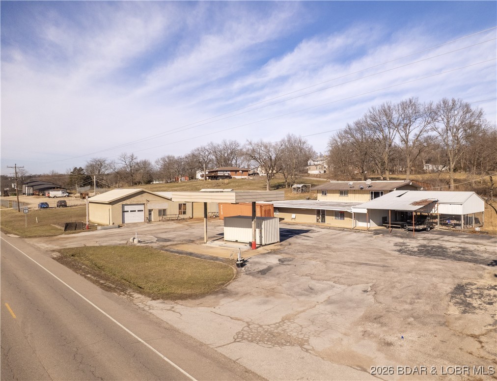 Once was a Fuel Station with Tire Repair Shop. In 2025 Traffic Count was 1517 per day! That's over 500,000 a year! This rare commercial and residential property offers the opportunity to live and work in one place while benefiting from growing highway traffic. The 3-bedroom home features main-level living, an open floor plan with vaulted ceilings, LVP flooring, updated windows, and a modern kitchen with custom cabinetry, tile backsplash, large island, gas stove, and hard-surface countertops. A covered patio, attached carport, and walkout lower level add everyday functionality. The former convenience store includes office space, kitchen area, two half baths, a shower, ample storage, and a large walk-in cooler. Multiple additional outbuildings provide shop, garage, and work space with overhead doors for equipment or vehicle access. Previously operated as a gas station, convenience store, bait shop, deli, and hardware location, this property offers excellent highway frontage with limited nearby competition and increasing traffic. Located in the School of the Osage District and a short drive to Lake of the Ozarks, it’s a versatile live-and-work opportunity.