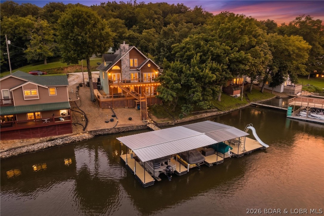 One-owner lakefront retreat offers the COMPLETE package—100 ft of shoreline, incredible views, gentle access to the dock!!! The 4-bedroom, 2.5-bath home was designed for gathering and entertaining, featuring cathedral ceilings, wood-burning fireplace, spacious kitchen with an island, and a second living room on the lower level with a bar/kitchen area! Primary bedroom on the main, two bedrooms and bath upstairs, another bedroom downstairs and the lower level half bath is plumbed for a shower already. Outside, enjoy flat parking for up to six vehicles, a three-slip dock with a large swim platform and slide plus the best area for fishing, swimming, and water sports the Lake has to offer! No HOA restrictions, nightly rentals are allowed, and fiber optic internet is available making this an exceptional personal getaway, full-time residence, or investment opportunity! New roof being installed!