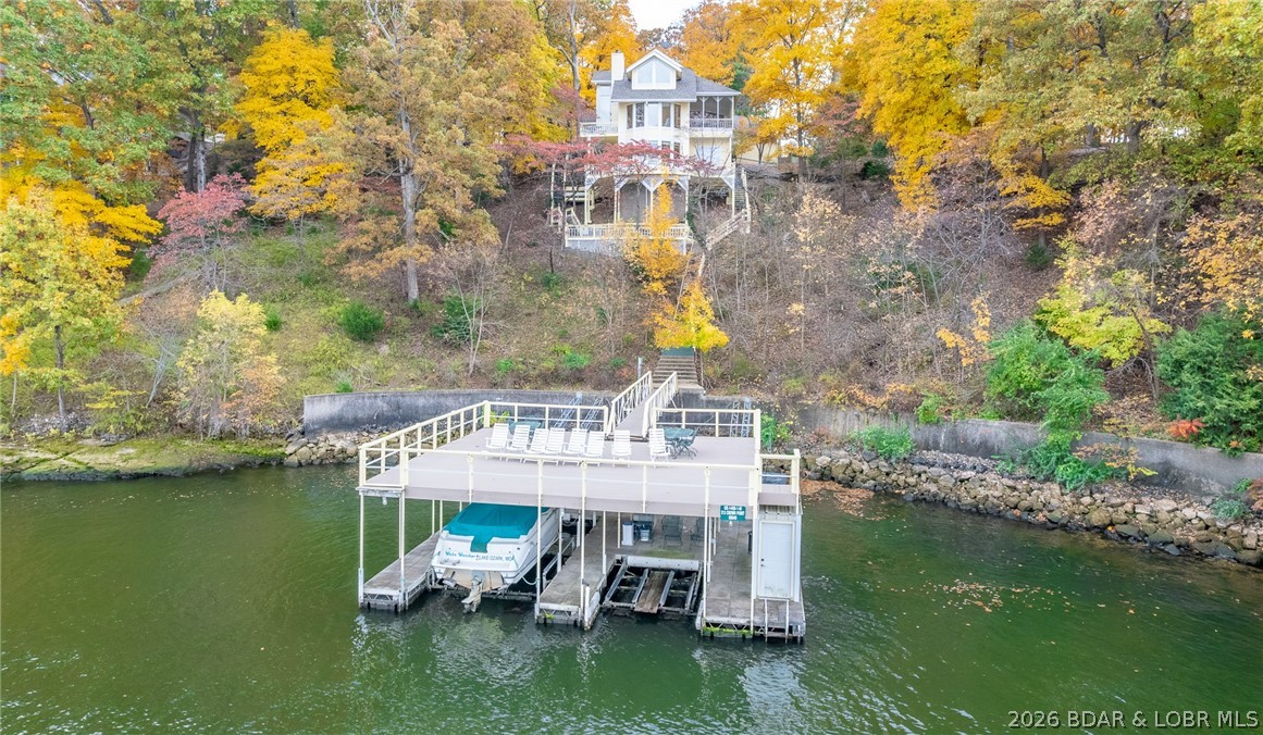 What a magnificent lake home on three lots in Four Seasons! This 3700SF, 4BR/5BA home was built in 1987 with beautiful materials and excellent construction. And wait until you see the two well dock with full upper deck.  Main level living has huge suite plus powder room. Top level consists of an enormous suite, Lower level has full bar, lakeside sitting room, half bath and two more large guest rooms, each with private vanity and share a Jack and Jill bath. Home has been immaculately maintained. Polished marble floors shine and the view of the main channel goes for miles. Custom cabinetry throughout, two car garage and plenty of room for addl parking, screened porch on main level, multiple lakeside decks. The Regal runabout and hoist is included, the double PWC hoist is included. This home is move in ready. Its also perfect for updating and has great original features that will easily translate into today’s décor. Setting allows for great privacy! Be sure to watch the video tour and contact the listing agent for plats and details. Amenities: indoor and outdoor pools, tennis & pickleball, clubhouse, boat launches, campground, storage and much more!