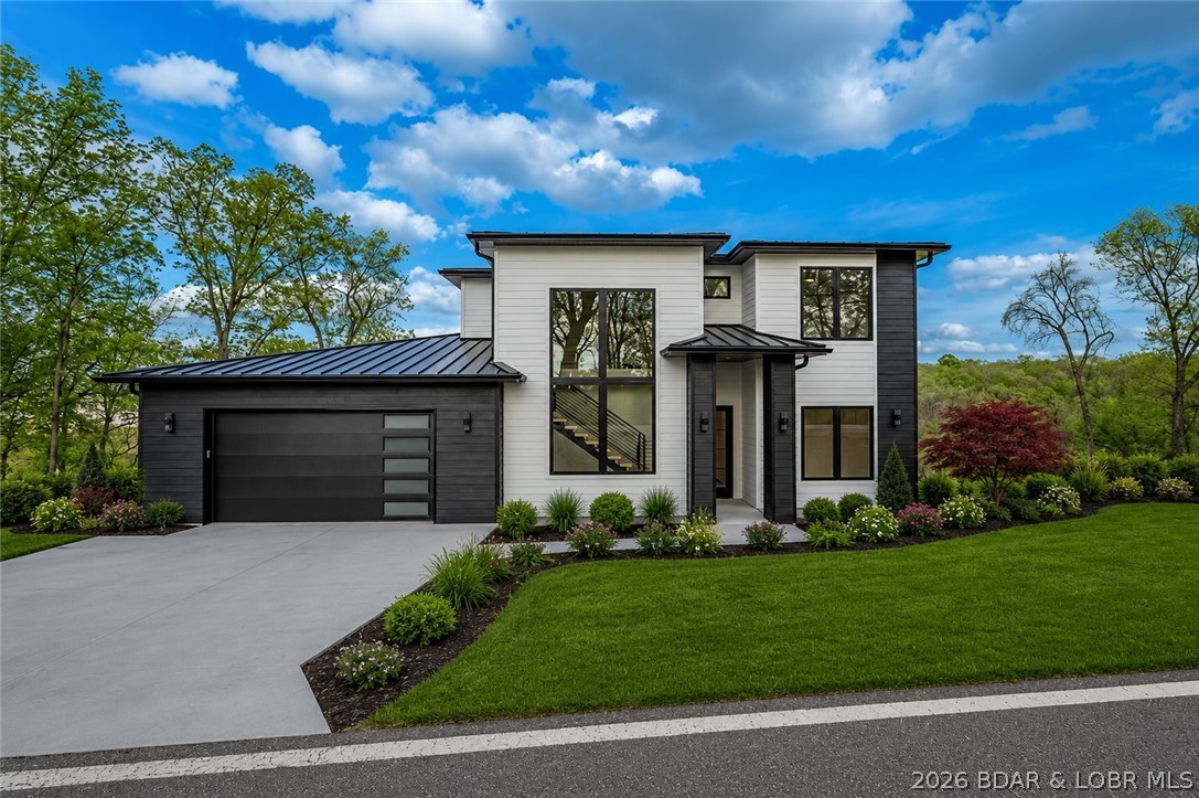 Some homes are nice… and some are impossible to forget. This stunning new construction home with lake views at the 3MM of the Osage offers nearly 3,000 sq ft and is perfectly located down HH just minutes from the Strip, waterfront dining, shopping, and entertainment. Designed for both entertaining and everyday living, this 5-bedroom, 3.5-bath home features 2 ensuites and a modern open-concept layout filled with natural light from a dramatic wall of Anderson windows and doors. A striking floating staircase makes an immediate statement, while the kitchen impresses with a waterfall island, custom blend of quartz and quartzite countertops, black and gold finishes, and Frigidaire Gallery appliances including a 36-inch gas cooktop. The living room fireplace creates a warm yet elevated gathering space. The primary suite feels like a private retreat with Italian tile, heated floors, soaking tub, and walk-in shower. Additional features include zoned HVAC, foam insulation, metal roof, oversized 2-car garage with golf cart space, available boat slips, backyard space for a pool at additional cost, and a $20,000 landscaping allowance.