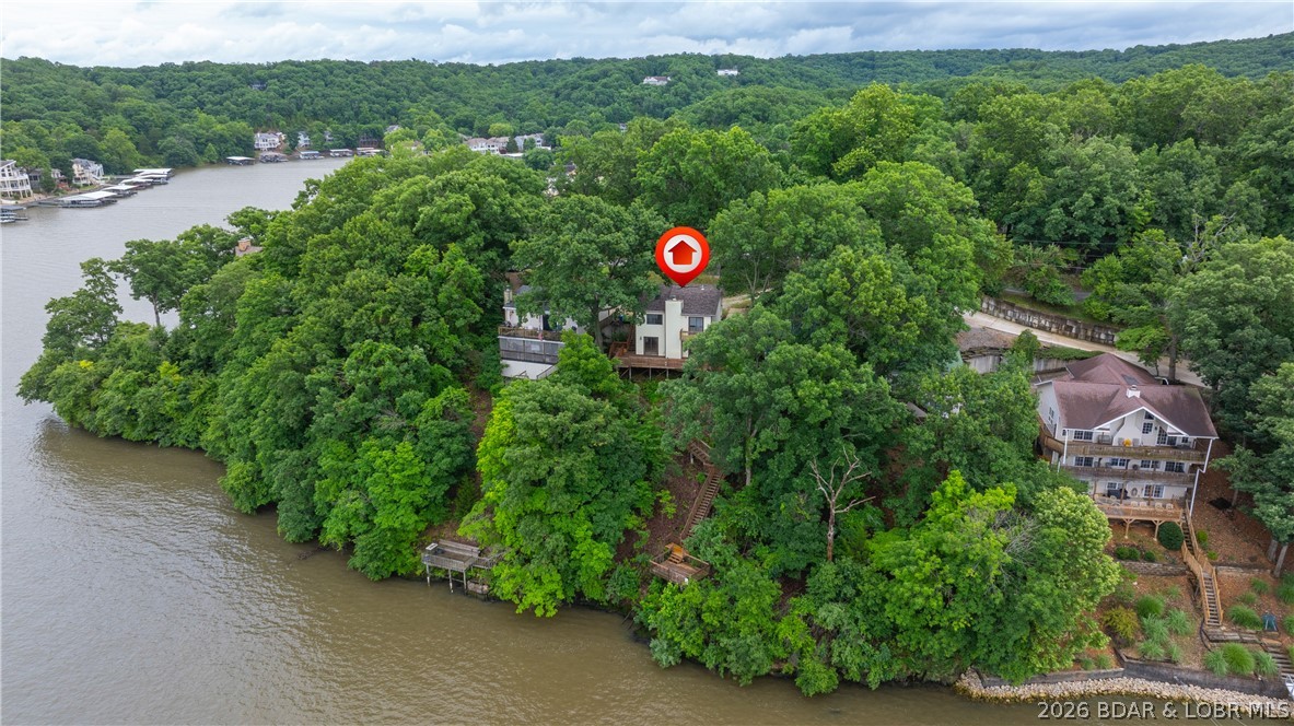 Enjoy panoramic views of the 30 MM on the Osage Arm and experience lakefront living at its finest. This 3-bedroom, 2-bath home offers 1,568 square feet of comfortable living space with expansive water views and easy access to some of the lake’s most popular destinations. By water, you're just minutes from Larry’s On The Lake, The Fish & Company, Bulldogs Beach House, and Captain Ron’s Bar & Grill. While no dock is currently in place, the property is permitted for a 40'x24' overall dock with a 12'x32' slip, providing the opportunity to create your ideal waterfront setup. Whether you're looking for a full-time residence, vacation retreat, or investment property, this home offers a prime location, incredible views, and endless possibilities to enjoy the Lake of the Ozarks lifestyle.