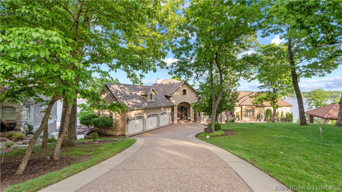 A home is officially on the market in the area’s most prestigious neighborhood, The Villages at Shawnee Bend. This premier neighborhood stands in a class of its own—and now you have the chance to live in the most sought-after luxury locations at the lake. This property has been updated with premium carpet, granite countertops, sinks, faucets, & mirrors throughout. Select hardwood flooring in the office, new tiled lower level & enhanced surveillance for both the home & dock. Resting on a generous lot with 127ft of beautifully manicured lakefront, it offers ideal cove protection & a sweeping main-channel view. Inside, you’ll be welcomed by tall architectural columns, a striking stained wood box ceiling, leading your eye straight to a custom wall mural designed by HGTV Artist Tom Moberg. The homes unique design offers an effortless flow with 5 bedrooms(one made into an office), 4.5 baths, two spacious living areas, work out room& a loft above the climate-controlled garage. Outdoor living shines here with two decks-one screened screened, a firepit area, & ample room to add the pool you’ve always envisioned. Photos simply can’t capture how stunning this home truly is. See it today!