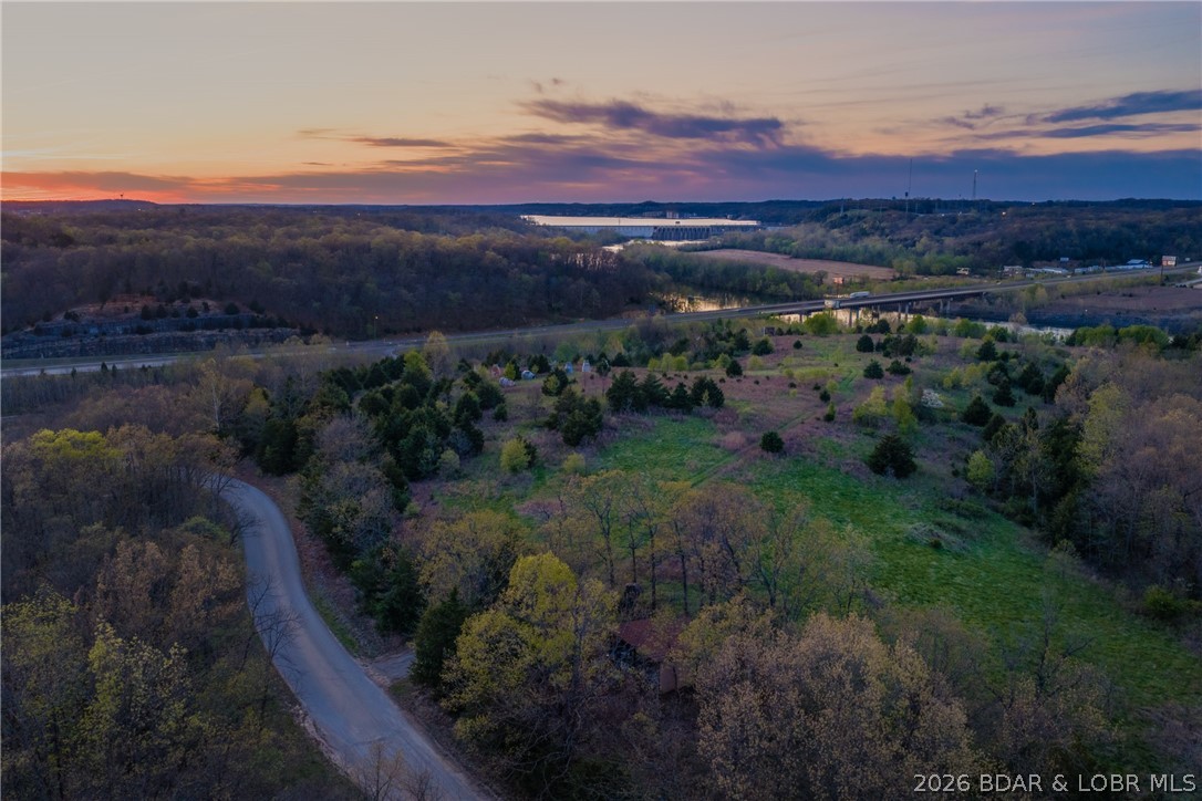 37± acres positioned at the front door to Lake of the Ozarks—the very first impression when arriving at the lake. Elevated high above Business 54 at the Bagnell Dam Blvd/HH & Route 242 corridor, this property delivers unmatched visibility, exposure, & panoramic views of the Osage River, Bagnell Dam, and the iconic Lake of the Ozarks sign. Rare opportunity to own one of the most strategic and visually striking tracts in the region. The land offers a gentle, mostly level topography, partly located in Lake Ozark city limits(C2 zoning) and partly in Miller County with no zoning—creating flexibility for a wide range of development options. Utilities are nearby, making this a practical as well as powerful investment. Surrounded by major retail & high-traffic destinations including Menards, Kohls, CVS, Aldi, and the theater.  All located within sight of 2 proposed casino developments, the growth potential here is undeniable. Ideal for a signature project—winery, restaurant, wedding venue, luxury resort, or mixed-use development—this property has the scale, setting, and presence to become a true landmark. If you’re looking to create something iconic at the lake, this is where it starts.