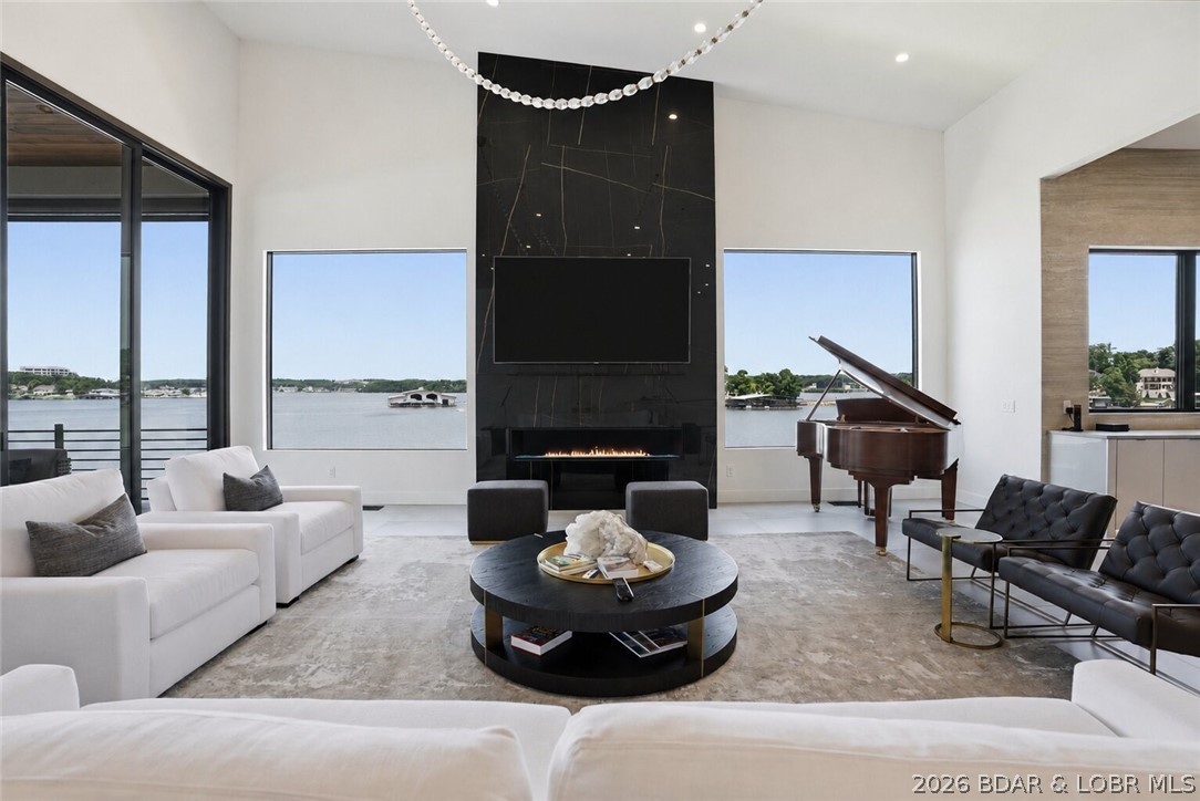 This is where striking architecture, curated design & next-level lakefront living come together. Situated on the best lot in the subdivision, this unique estate offers 176 feet of cove protected shoreline, main channel views & incredible sunsets. The collaboration between the owner & a top KC design firm makes every space feels intentional, sophisticated, & effortlessly livable. Offered completely turnkey, this home showcases stunning finishes, custom cabinetry, dramatic indirect lighting & walls of glass that keep the Lake front and center. A floating staircase with illuminated accents serves as a true architectural centerpiece, while premium Wolf & Sub Zero appliances anchor the chef's kitchen. Technology is seamlessly woven throughout with a fully integrated Control4 smart home system, golf simulator, theater, outdoor kitchen & multiple lakeside gathering spaces for entertaining. With pool & exterior maintenance handled by the HOA, you can relax & not worry about upkeep. With plenty of room for any boat dock you can dream up, this property delivers a rare blend of luxury & convenience. For buyers seeking a statement home, 125 McLaren Drive is in a class of its own.