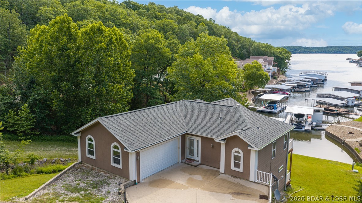 Lakefront living in a peaceful cove at the 26mm! Breathtaking views! Fresh paint & new carpet - Move-in Ready! This waterfront retreat offers quick boat access to Lake of the Ozarks' favorite waterfront attraction: Margaritaville, Land Shark +more. Multiple outdoor living spaces maximize the lake views & outdoor entertainment. Complete w/ 12x30 dock, boat lift, Monark Seville 24' pontoon w/150HP Yamaha outboard, private boat ramp, paved roads - NO gravel, HOA-covered water/sewer, LEVEL parking for 4+ vehicles + attached garage. Open-concept floor plan features stunning hearth room w/ soaring cathedral ceilings, gas fireplace, & dramatic windows showcasing the lake. Chef's kitchen offers stainless steel appliances & sunny breakfast nook that opens to large screened porch overlooking the water. Main-level primary suite features coffered ceilings, a spacious walk-in closet, spa-inspired bath w/ double vanities, jetted tub, walk-in shower & private deck access. Walk-out lower level offers high ceilings & windows galore w/ spacious lakeside family room + 3 add'l bedrooms including 2nd primary suite w/ full bath + oversized walk-in closet.  Bring your suitcase & enjoy life! Don't wait!!!